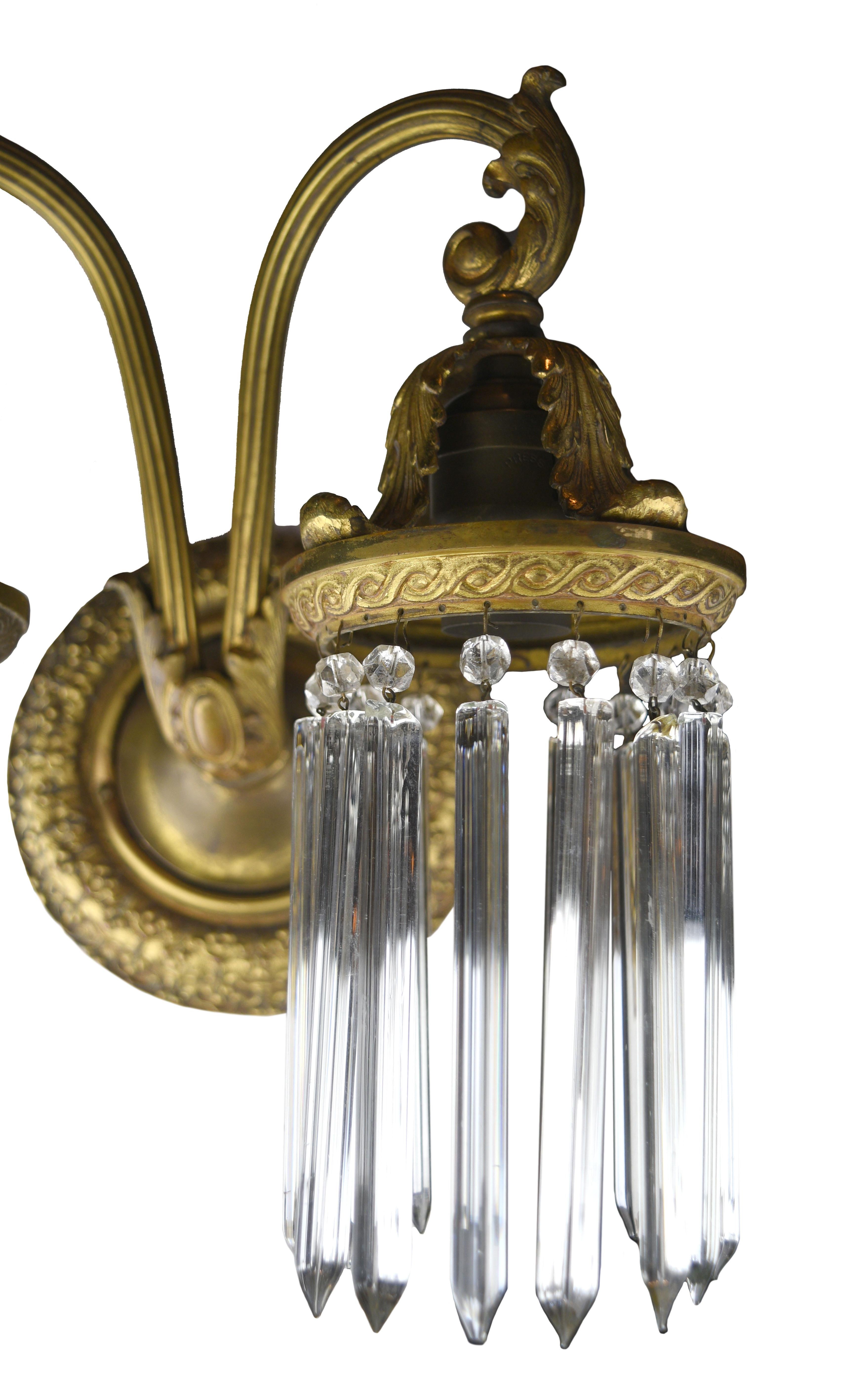This two-arm brass sconce features 30 elegant hanging crystals and a winding floral design. The lovely brass finish perfectly contrasts the shimmering luminosity of the crystals.