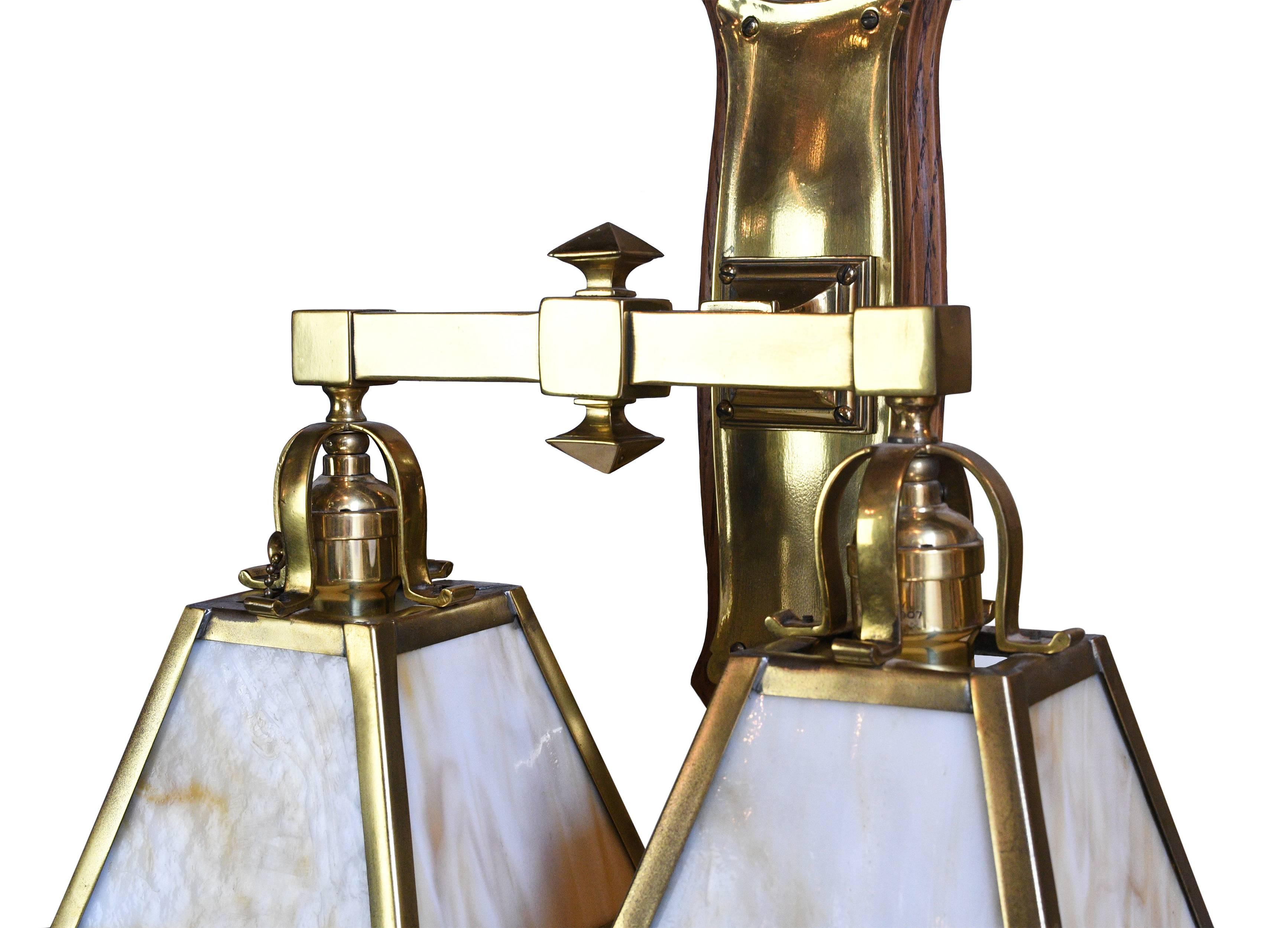 This two arm sconce is very special. It has a shiny brass body and wood back plate. The combination of bright metal and dark wood is charming and adds a lot of character to this fixture. Additionally, the glass of the shades has a rich, subtle