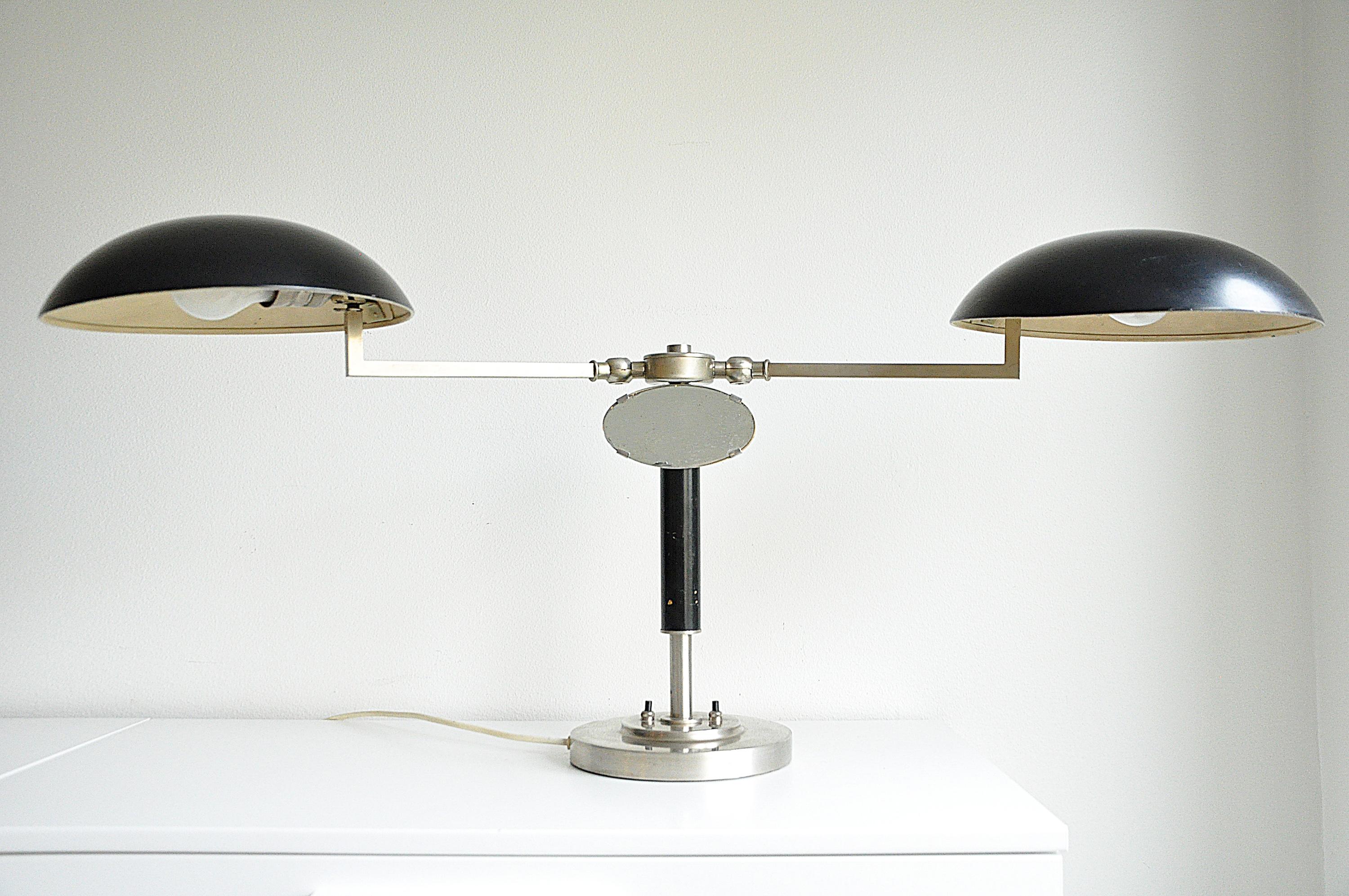 Rare two-arms table lamp with a small mirror, circa 1930s. 
Unknown maker. 
Adjustable shades. 
Width - shades folded inside ca 61 cm, 
Width - shades facing outwards ca 98 cm.

Original wiring. We recommend this lamp to be rewired following the