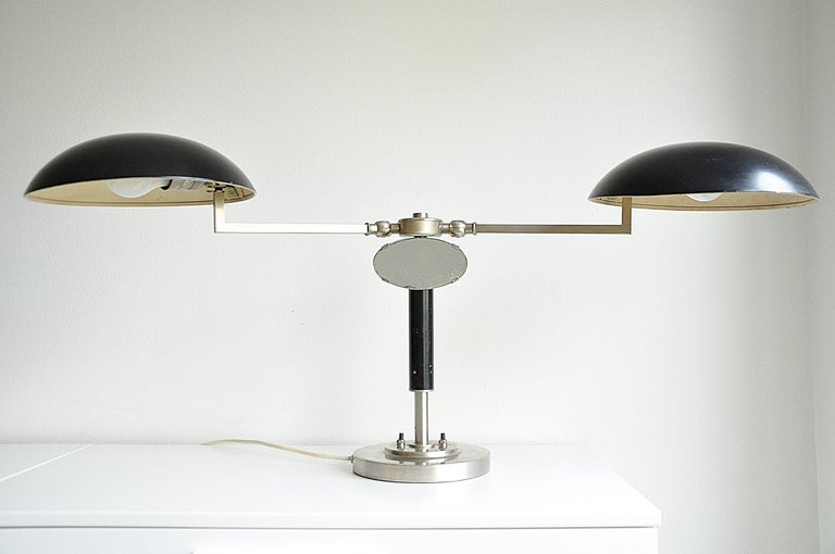 Rare two-arms table lamp with a small mirror, circa 1930s. 
Unknown maker. 
Adjustable shades. 
Width - shades folded inside ca 60 cm, 
Width - shades facing outwards ca 98 cm.

Original wiring. We recommend this lamp to be rewired following