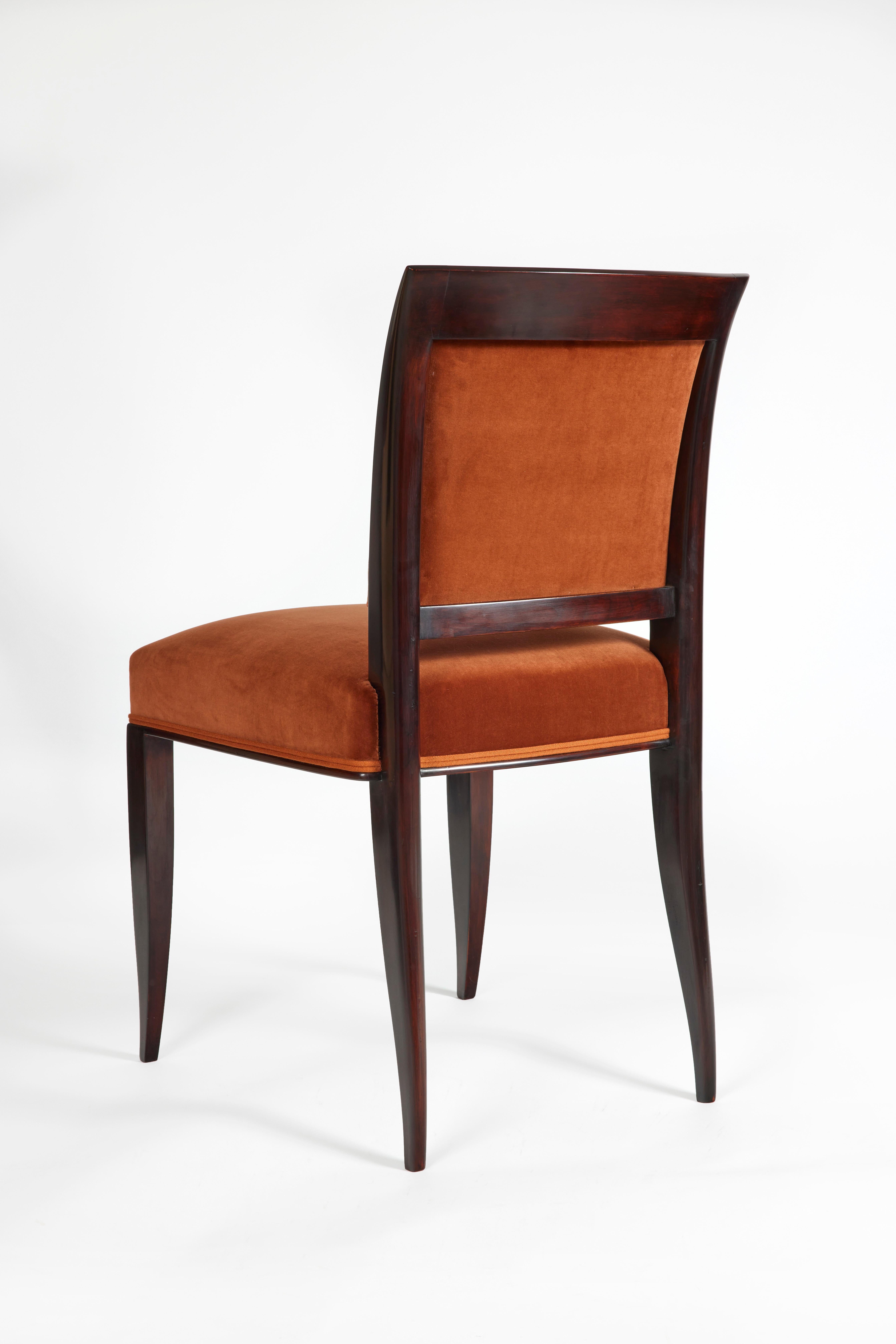 Set of chairs for the dining room. 
Two armchairs in stained beech with legs forming curved sabers extending to the front in arm supports, 
flared arms and slightly hollowed out in the upper part, curved back forming a return to the outside, seat
