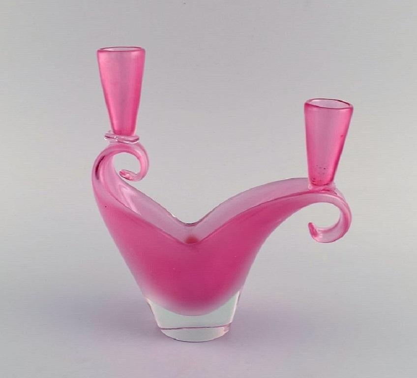 Two-armed Murano candle holder in pink hand-blown art glass. 
Italian design, 1960s.
Measures: 20 x 19 cm.
In excellent condition.
Sticker.