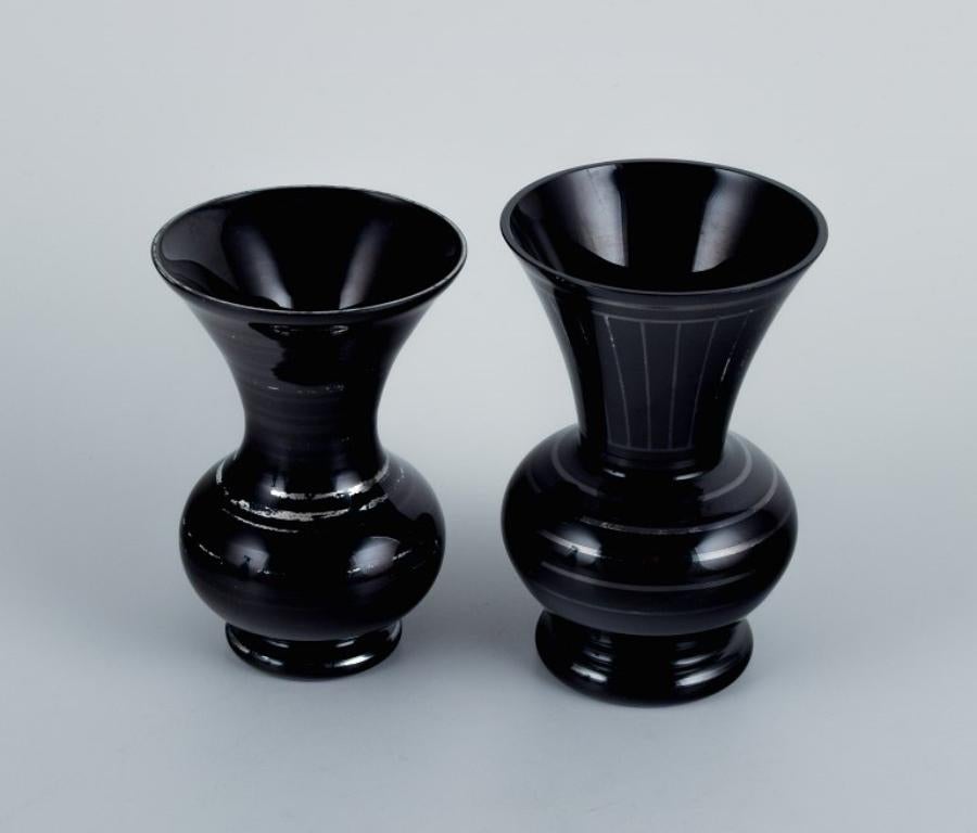 Due vasi in vetro Art Deco, Germania. Con intarsi orizzontali in argento.
1930/40s.
In ottime condizioni con lievi segni di usura.
Dimensioni del vaso più alto: H 12,0 x P 8,0 cm.