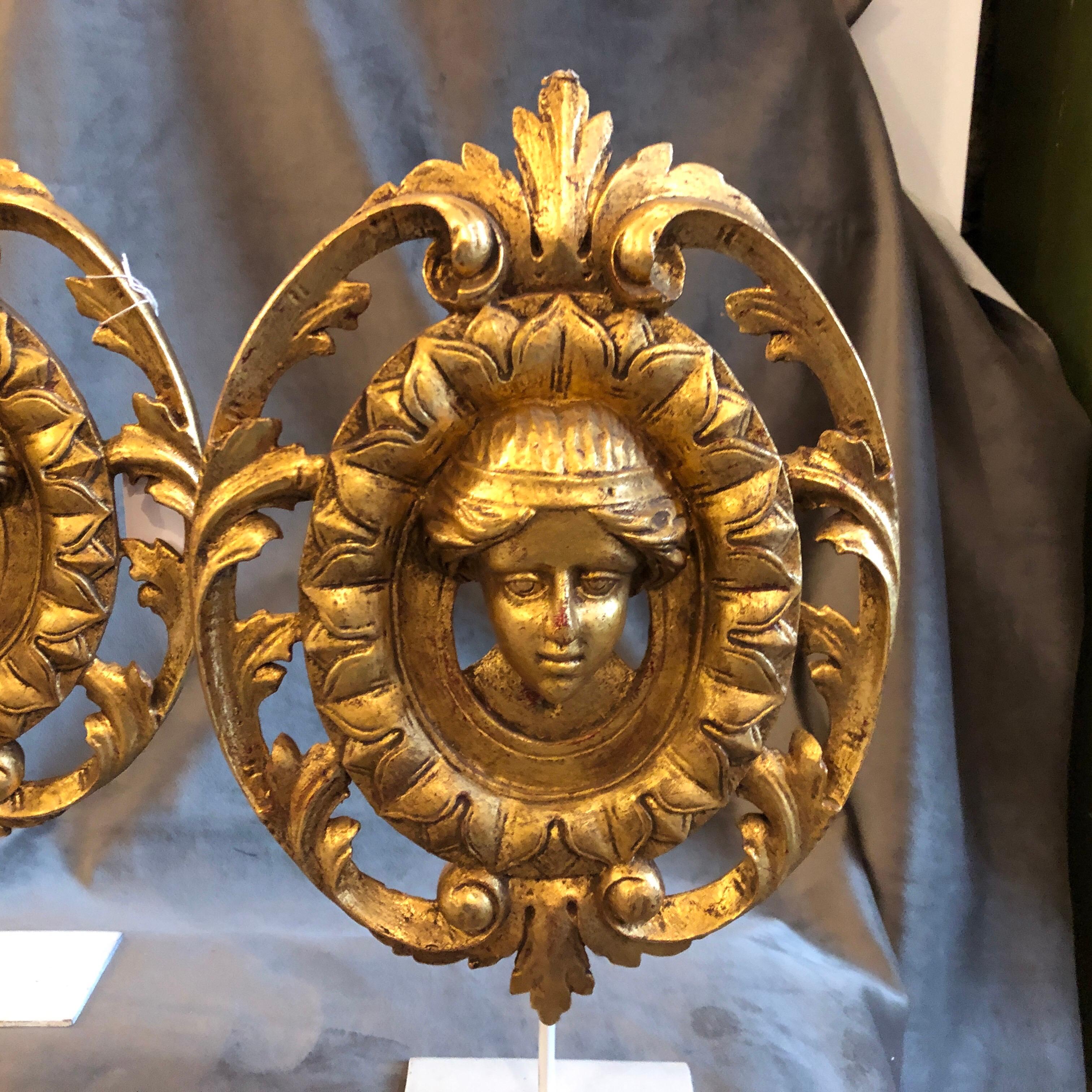 Set of two gilded wood friezes hand carved in Italy in 1900. Probably they came from a door or a furniture, they are mounted on a white painted metal pedestal.