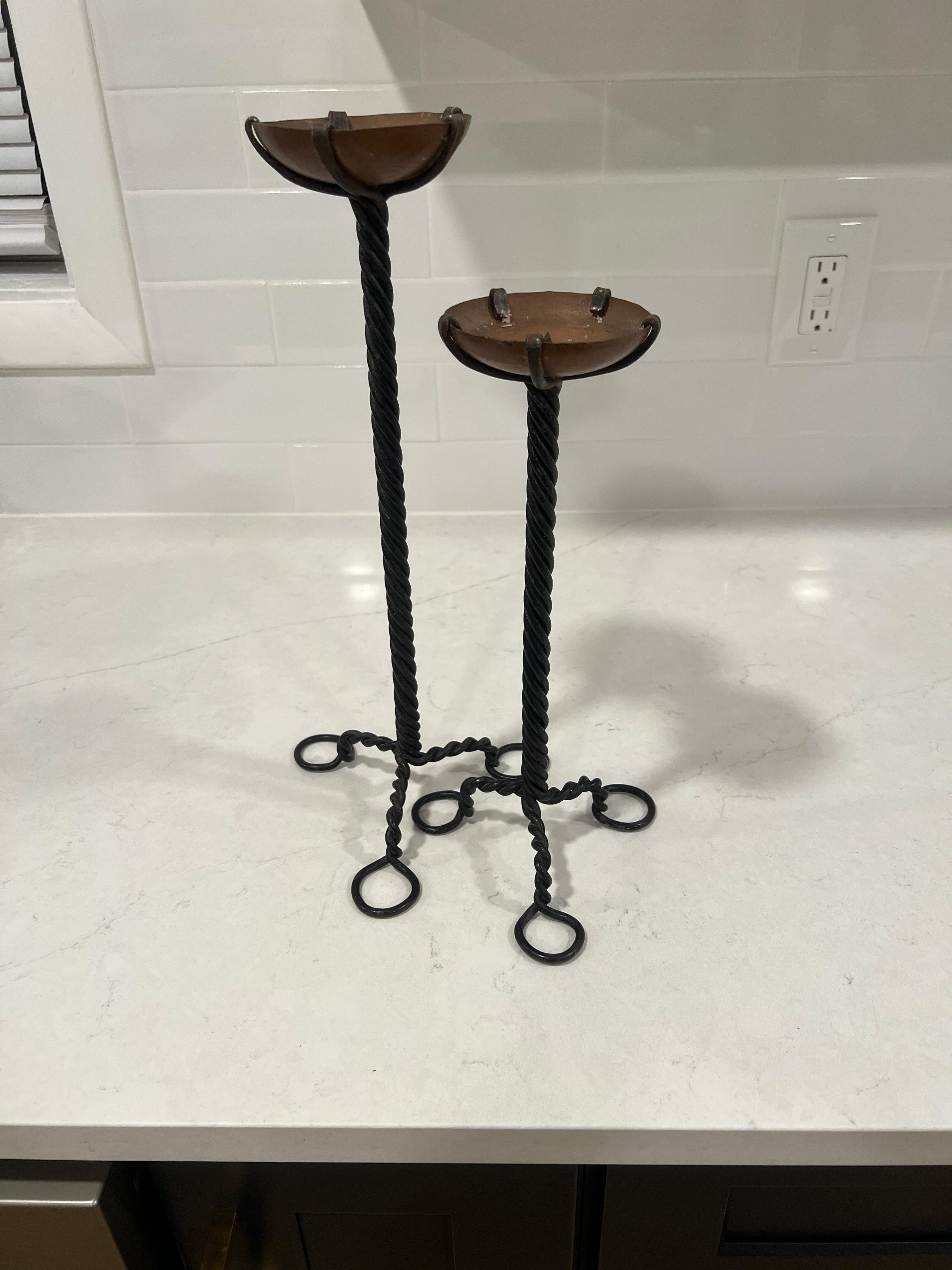 American, early 20th century.

A two piece grouping of Arts & Crafts Period candlesticks. Each constructed with a twisted wrought iron tripod stem and topped with a copper open bowl to top. Unmarked.

Large 14.875