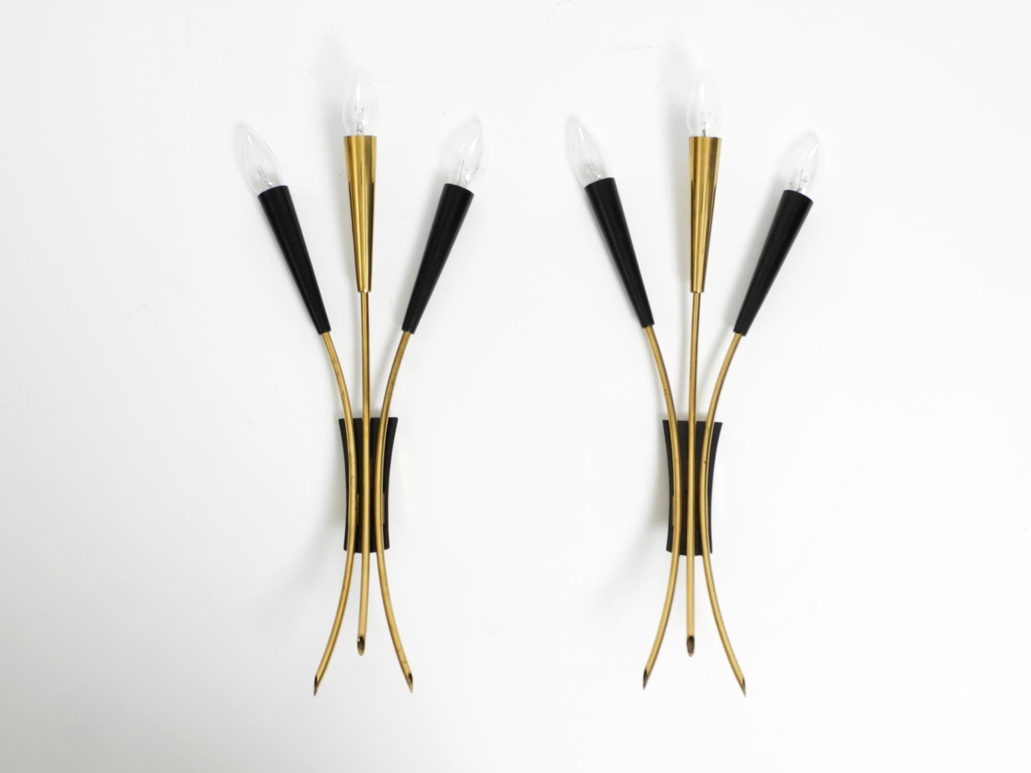 Un par de preciosas lámparas de pared Sputnik Mid Century grandes de 3 bombillas fabricadas en latón.
Las lámparas son totalmente de latón, incluidos los conos. Sólo las placas negras están hechas de un metal diferente. Las dos bolsas exteriores