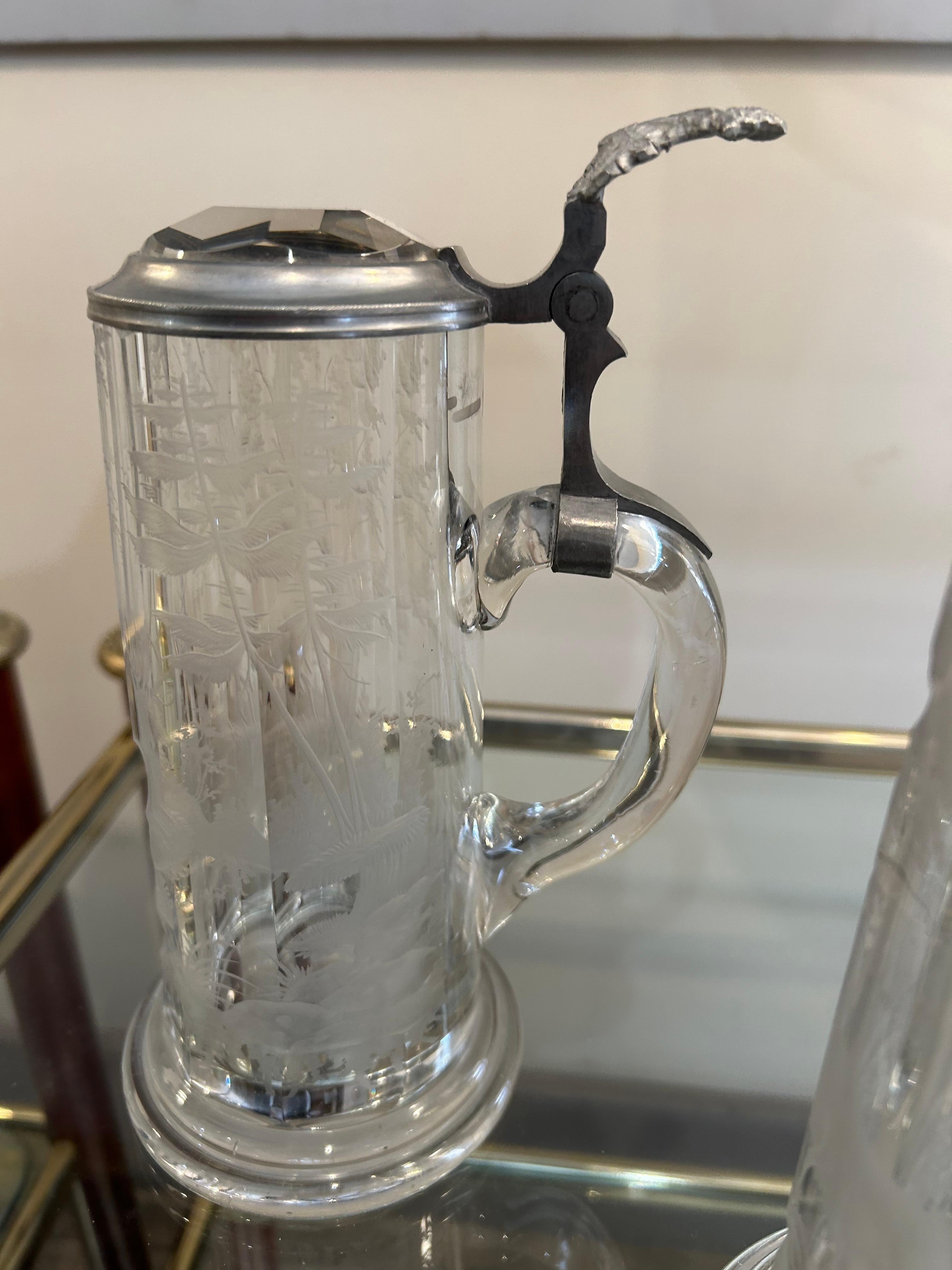 Bonjour ! Il s'agit de deux chopes à bière en verre taillé ou gravé, avec un couvercle en métal, en étain. Voici quelques faits intéressants à leur sujet :
1. Style et époque : Ces chopes ressemblent aux verres à bière traditionnels d'Europe