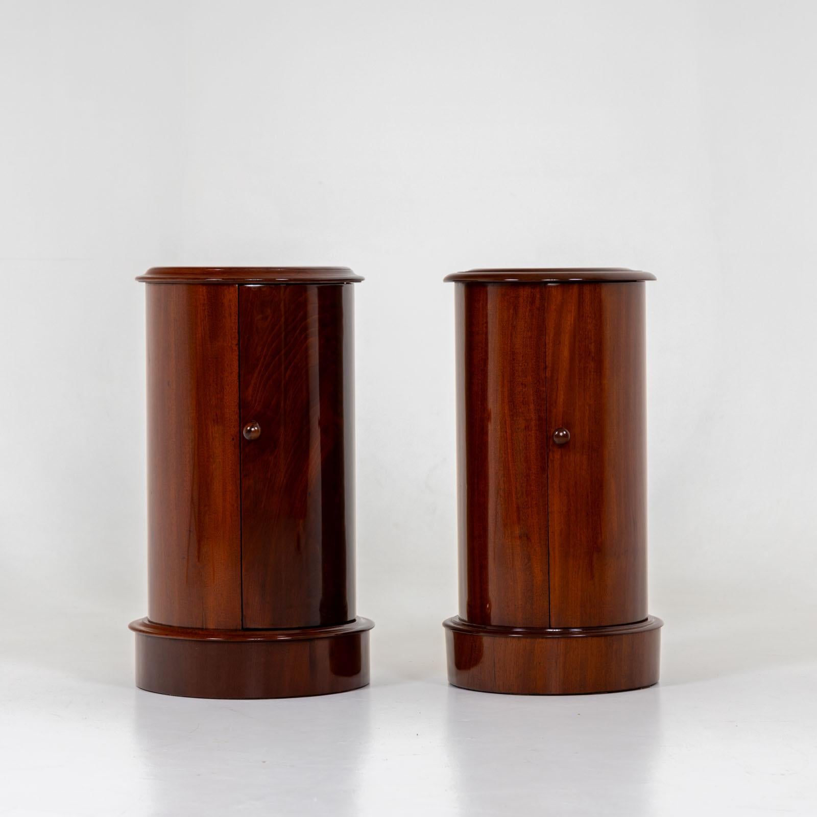 Two drum cabinets, each with one door and marble inlay on the surface. The cabinets are made of mahogany and have been polished by hand. The cabinets are not a real pair, but are similar enough to enrich any living room as a duo.