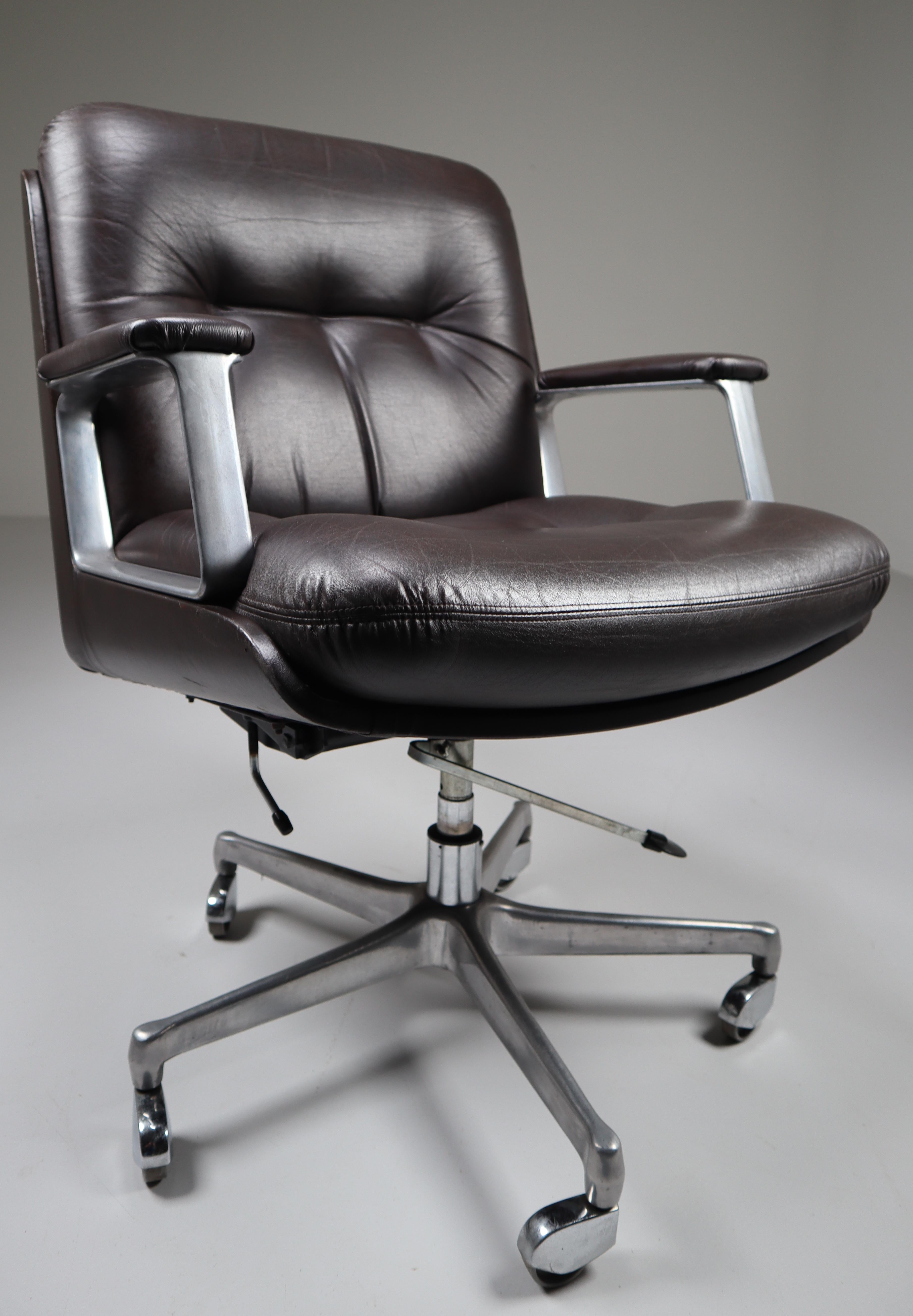 Executive office armchairs by Osvaldo Borsani for the Italian manufacturer Tecno features a elegant brown leather body with a generously proportioned button-tufted leather seat and back and floating on a five-pronged rolling adjustable cast aluminum