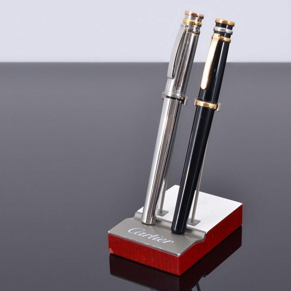 Elevate your writing experience with this exquisite set of two Cartier pens and stand, crafted with precision and sophistication by Cartier in France. Made from high-quality materials including metal and plastic, each component of this set exudes