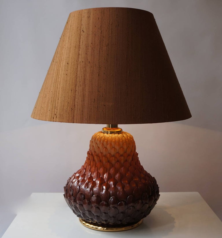 Two Italian brass table lamps with ceramic artichoke leaves. In the manner of Maison Charles. France, 1950s. 

Diameter ceramic base 39 cm.
Height ceramic base 35 cm.
Height of ceramic base with brass lamp holder 47 cm.
Weight 8 kg.

Shades shown