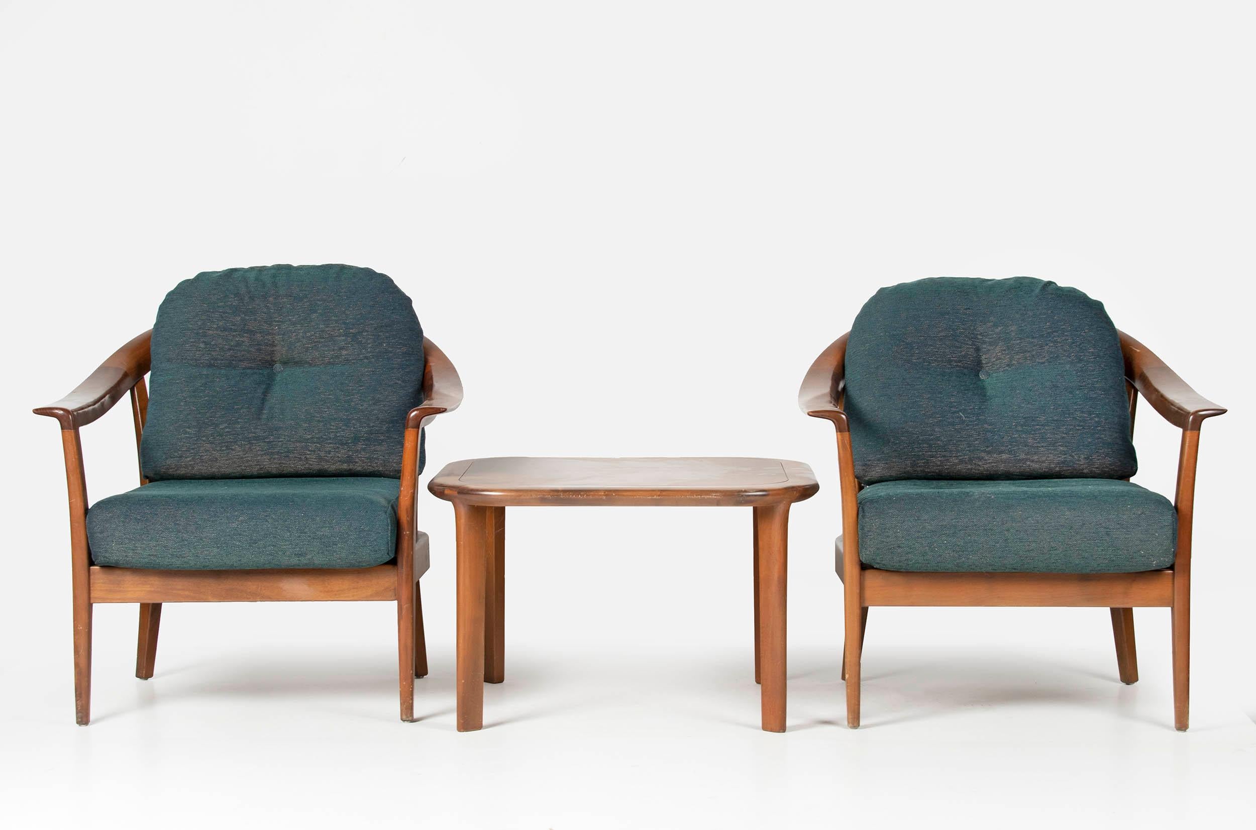 Two easy chairs with a side table from the German brand Wilhelm Knoll. The chairs are made of cherrywood, the wood has a warm, blond-brown color. The cushions have recently been fitted with new upholstery. This is a sturdy dark green, soft mixed
