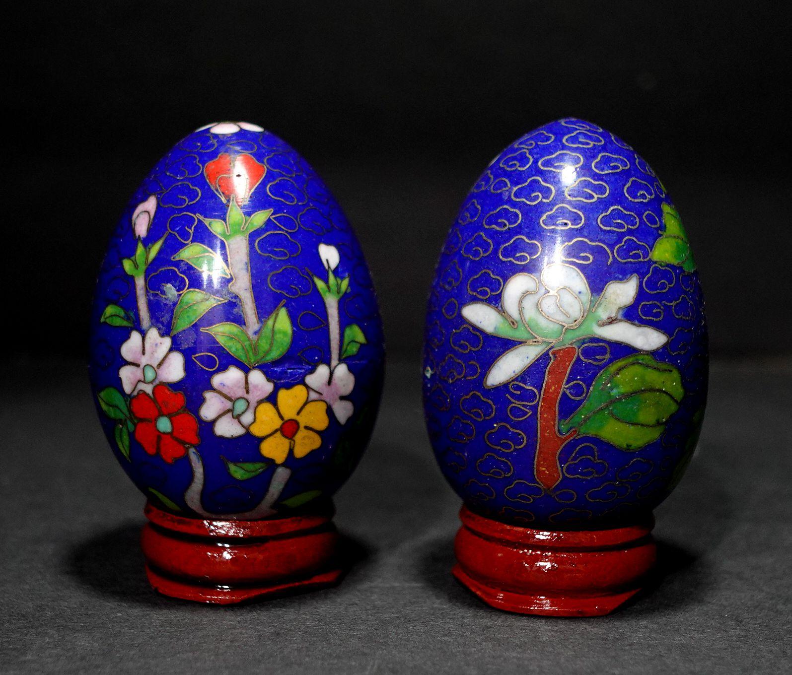 Presenting two beautiful Chinese cloisonné enamel eggs depicting flowers with wood stands, early 20th century.