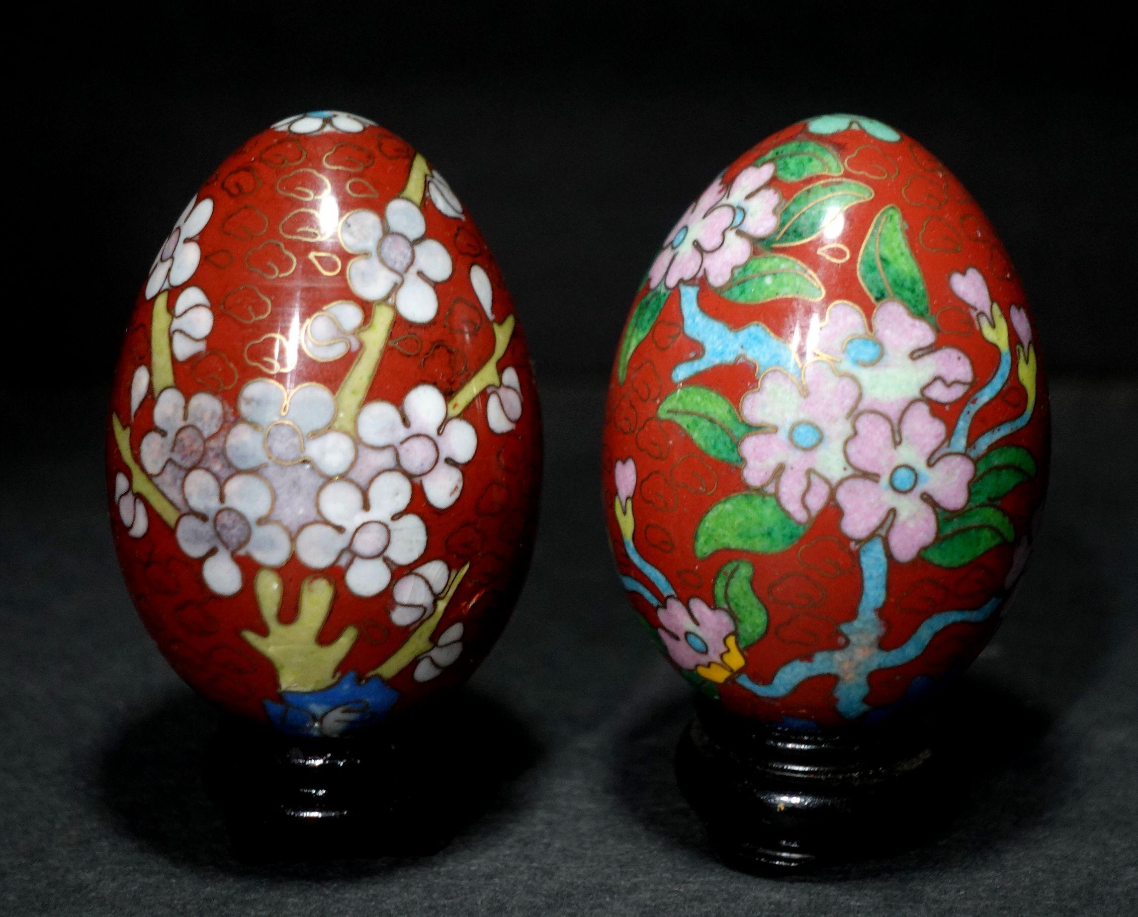 Presenting two beautiful Chinese cloisonné enamel eggs depicting flowers with wood stands, early 20 century.