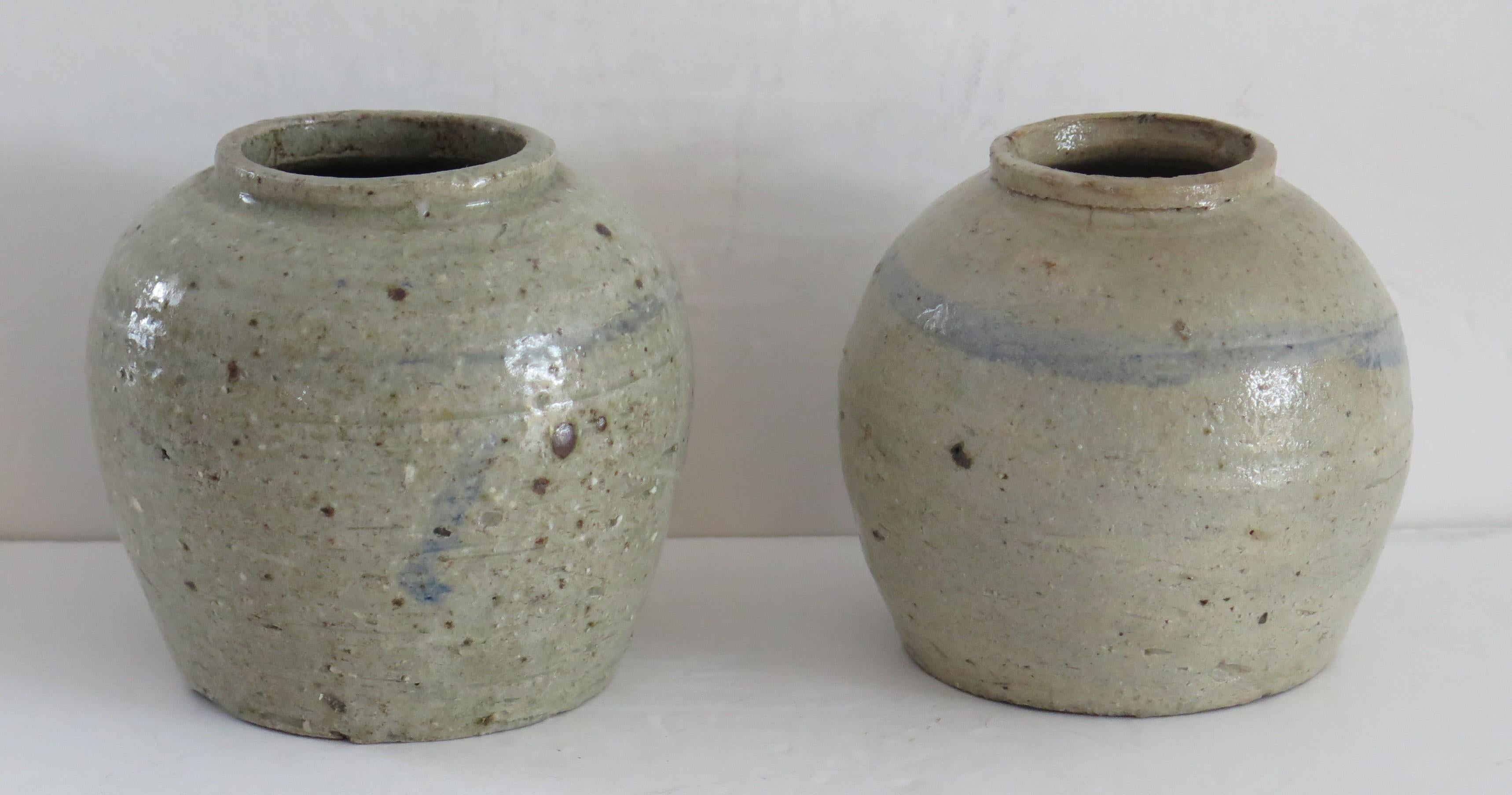 This is two similar Chinese handcrafted ceramic provincial jars with a light celadon glaze which we date to the Ming period of the early 17th century or possibly earlier.

The jars are hand potted with short necks and simply decorated with a ring