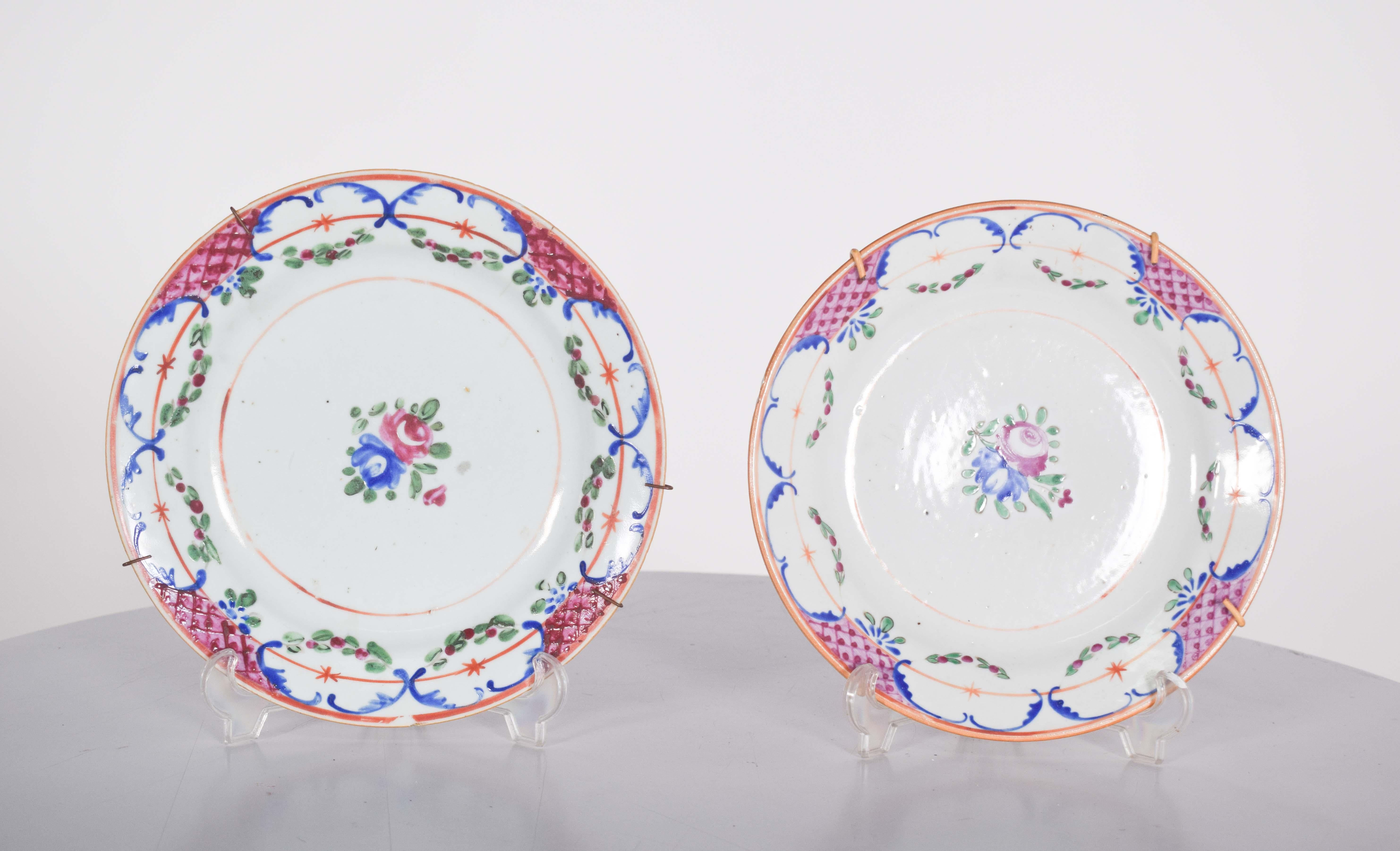 Two plates, in Chinese porcelain for export, displaying delicate and elegant decoration, possibly of European origin. They feature a refined floral pattern, hand-painted in vibrant shades of pink, blue, green and red, with ornamental details in gold