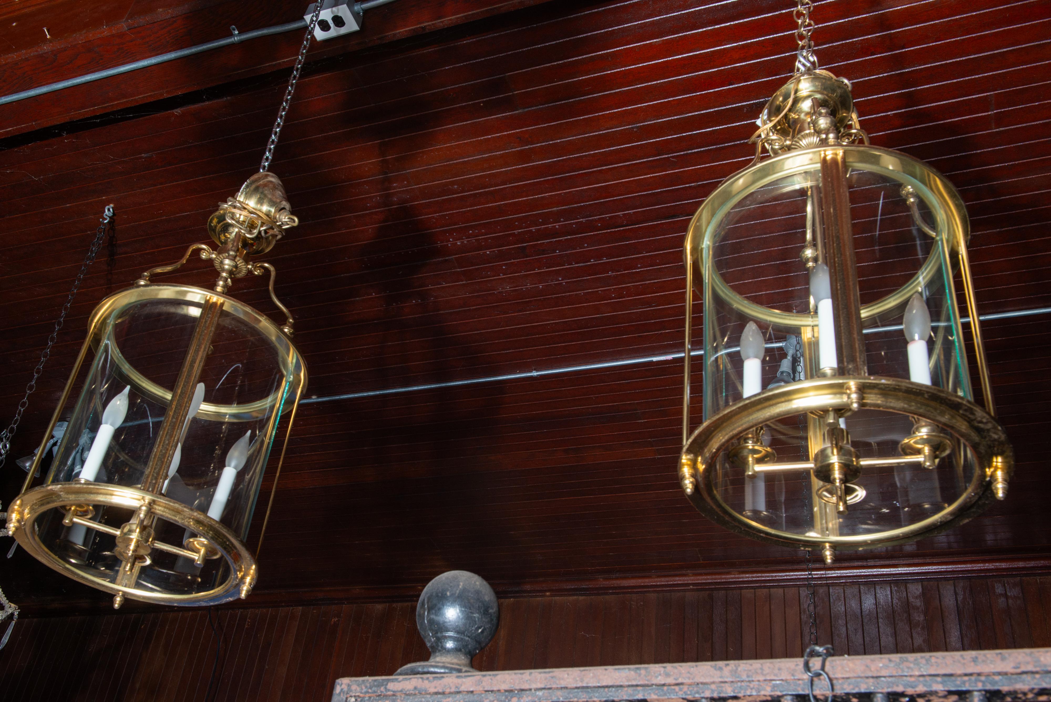 Two classical American four light cylindrical brass lanterns with curved glass panels. Hardwired with original canopies included.