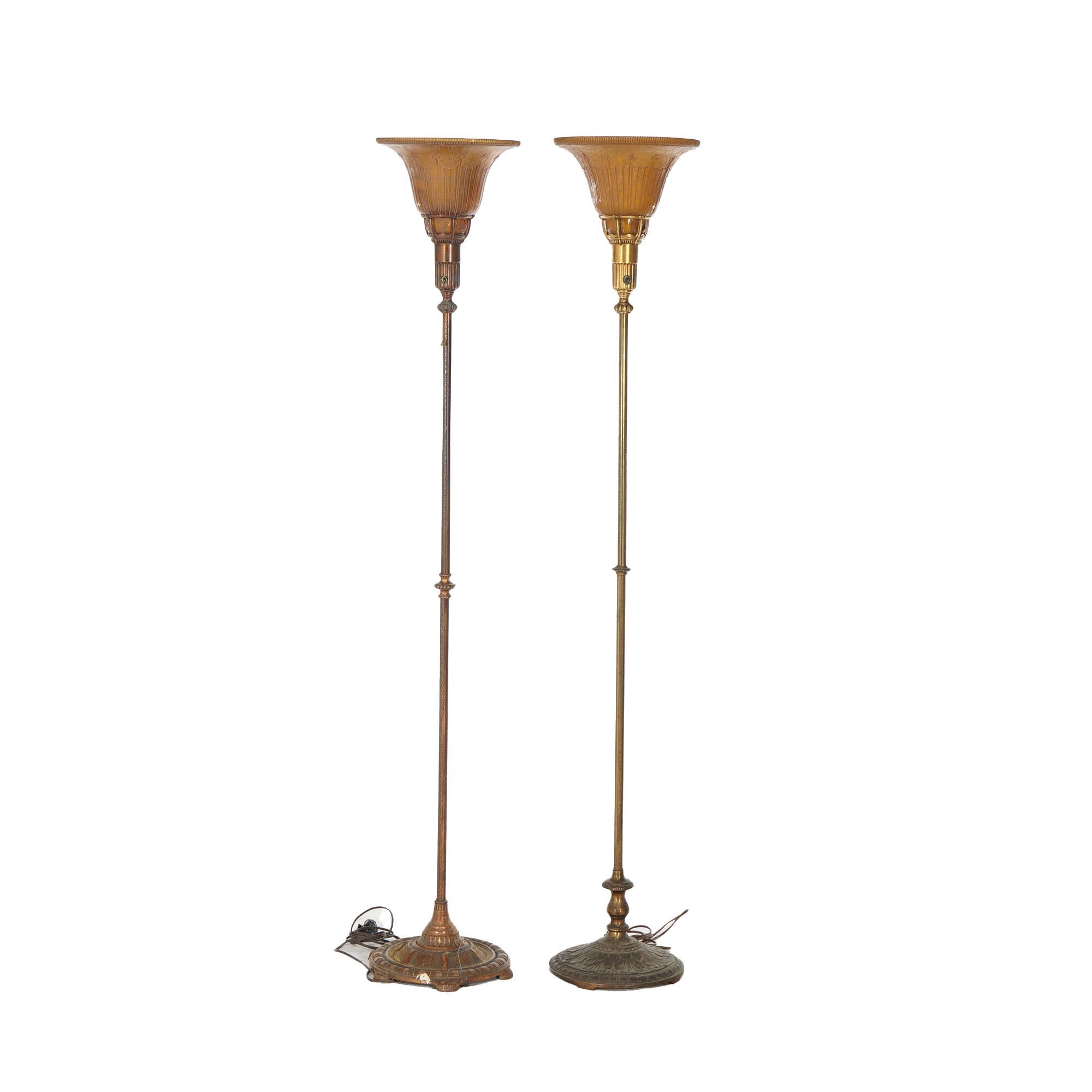 Two Classical style torchiere floor lamps by Lightolier offer gilt metal bases with amber glass shades, 20th century

Measures - 66.25