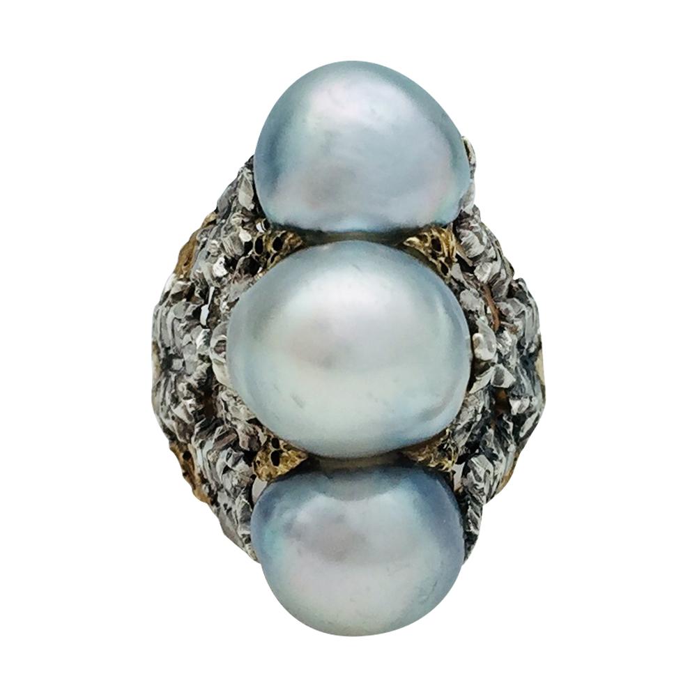 A 750/000 yellow and white gold Buccellati ring, centred with a three baroque shaped light grey pearls line, shouldered with foliage, enhanced with rose cut diamonds. 
Pearls dimensions: about 9 - 11 mm.
Ring size : 5.75 can be slightly sized. 