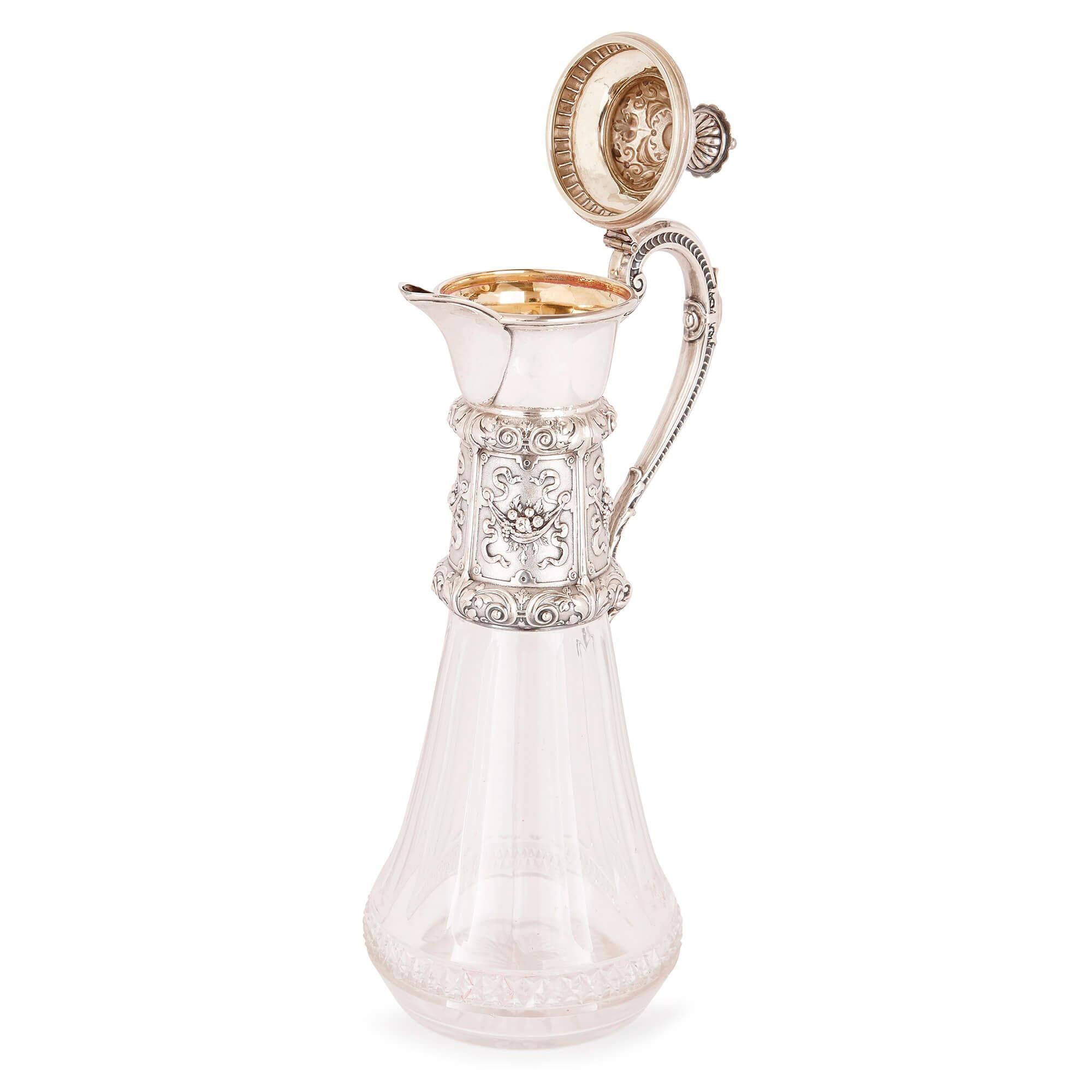 These exquisite jugs have been expertly crafted in glass and are mounted with sterling silver necks, spouts, handles and lids. 

The broadest part of the glass base, just above the bottom of each jug, is articulated by a decorative band, where the
