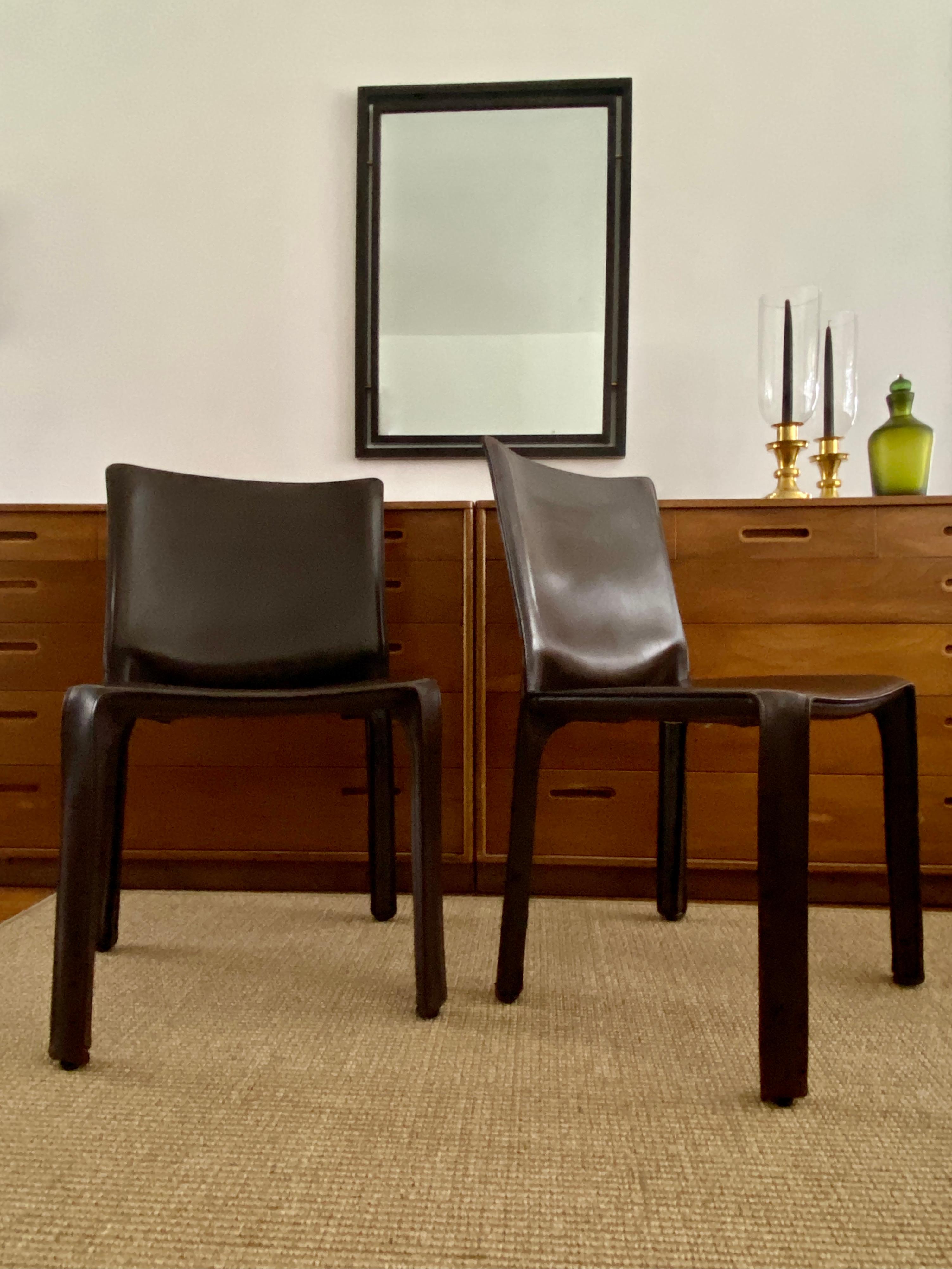 A pair of dark brown, saddle leather CAB 412 side chairs designed by Mario Bellini for Cassina in 1977. This pair of chairs are of newer production. The chairs stand approximately 32 inches tall at the back, 17 3/4 inches high at the seat, the seat
