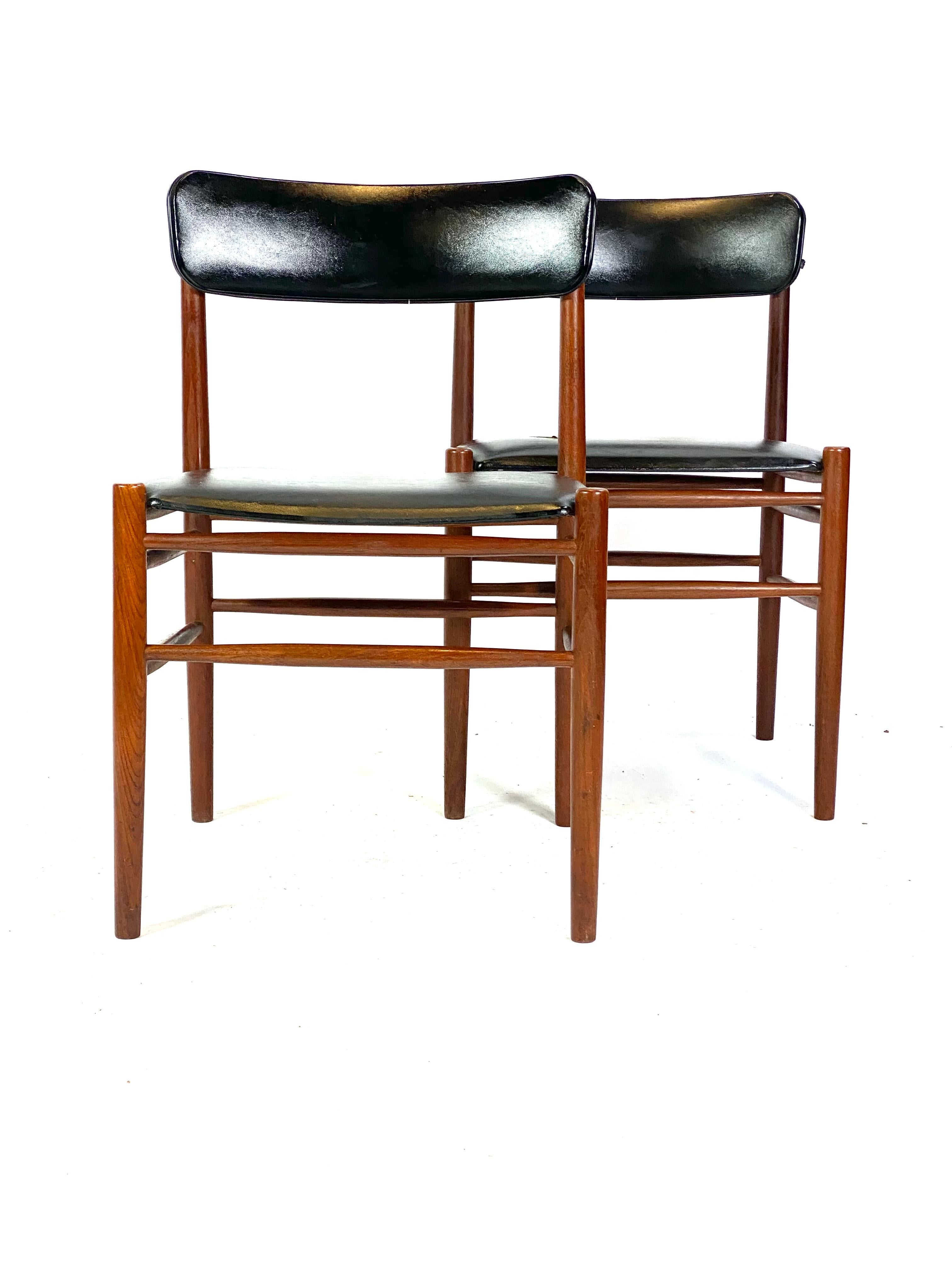 Two dining room chairs in teak and upholstered with black leather of Danish design from the 1960s. The pair is in great vintage condition.