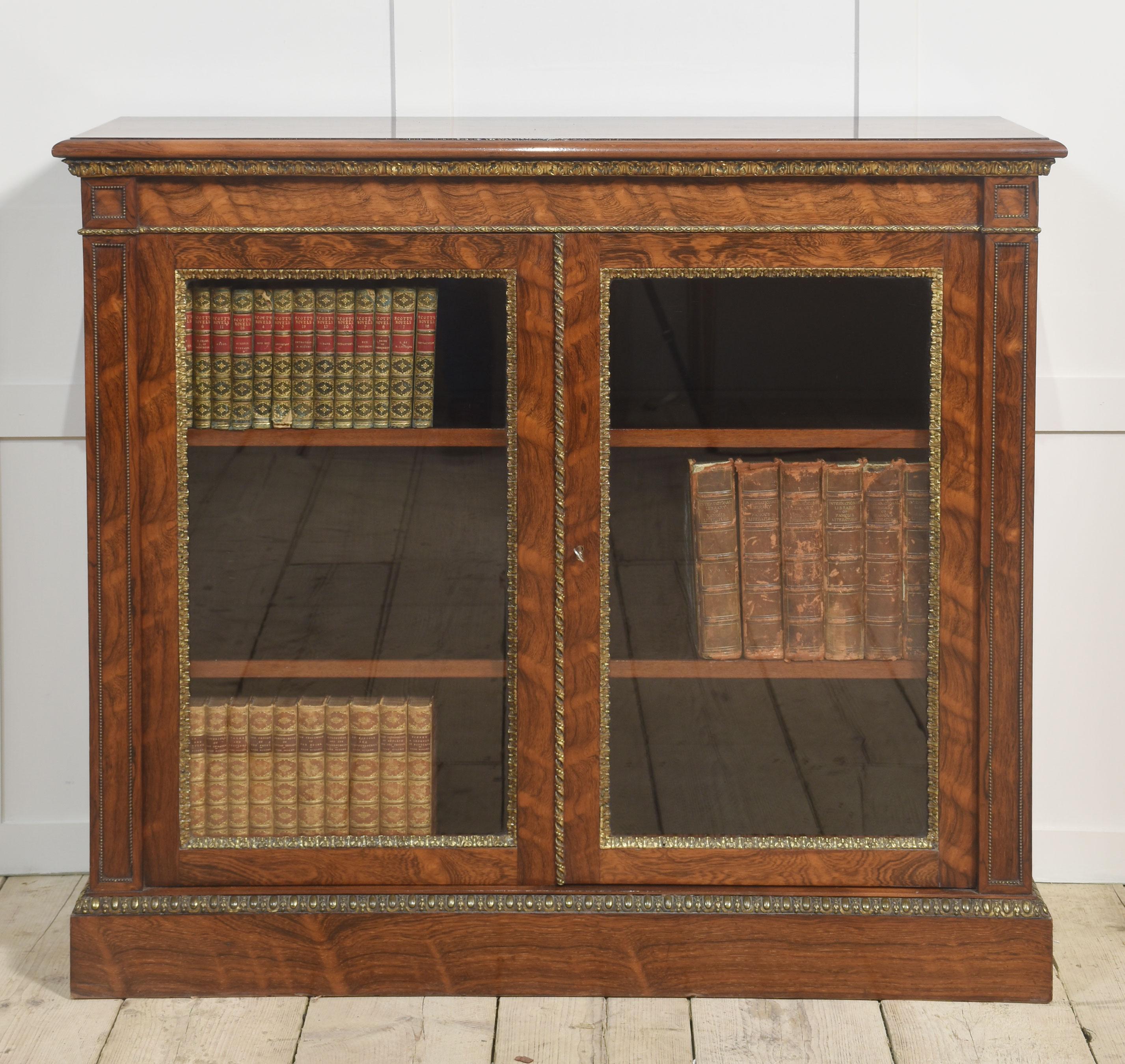 Bibliothèque à deux portes de Holland and sons. Le plateau, bien dessiné, comporte des montures en laiton. Au-dessus d'une paire de portes vitrées s'ouvrant pour révéler un intérieur à étagères réglables. Flanqué de colonnes moulurées avec bordure
