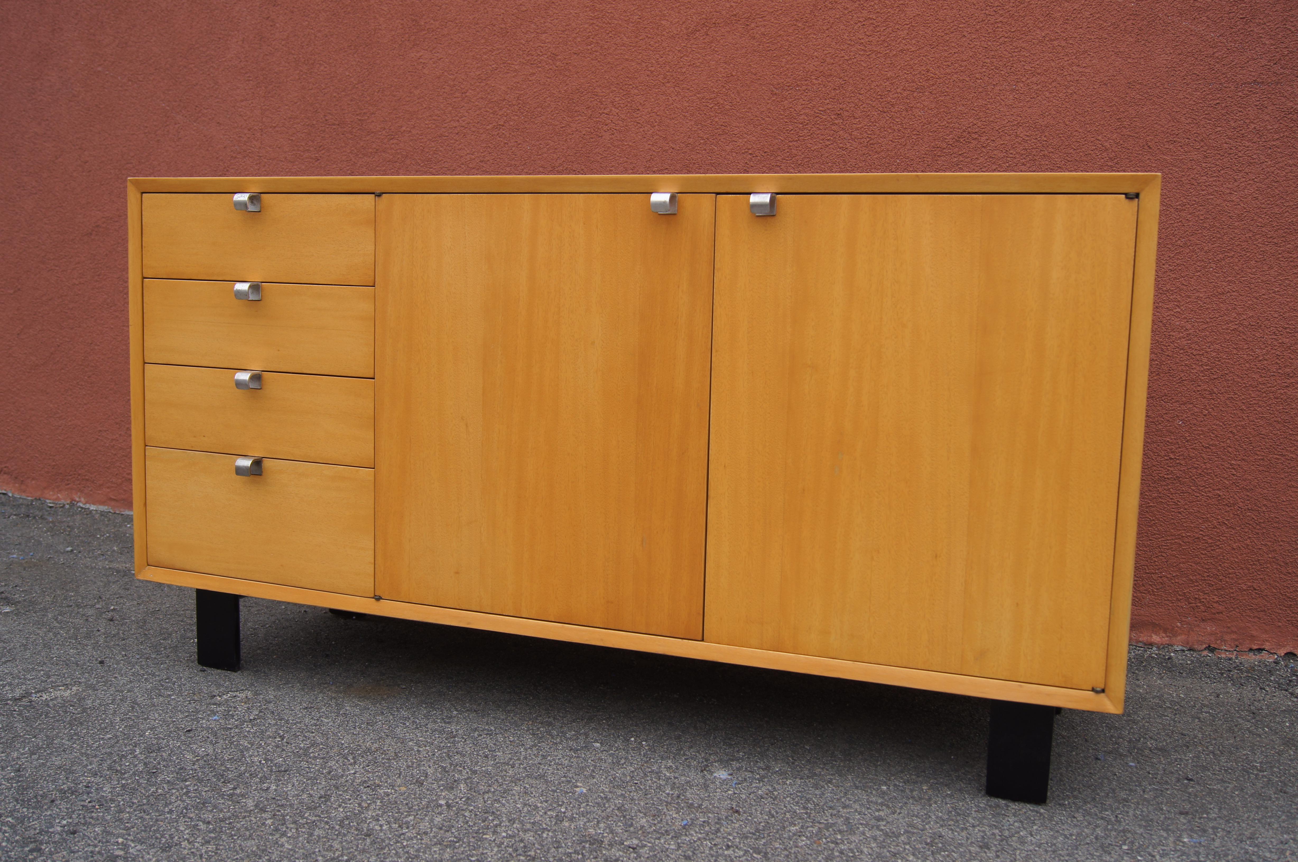 George Nelson designed this comb-grain oak cabinet for Herman Miller as part of their Basic Cabinet Series, sometimes referred to as the Primavera line. The case sits on ebonized block feet. To the left are four short drawers; on the right two doors