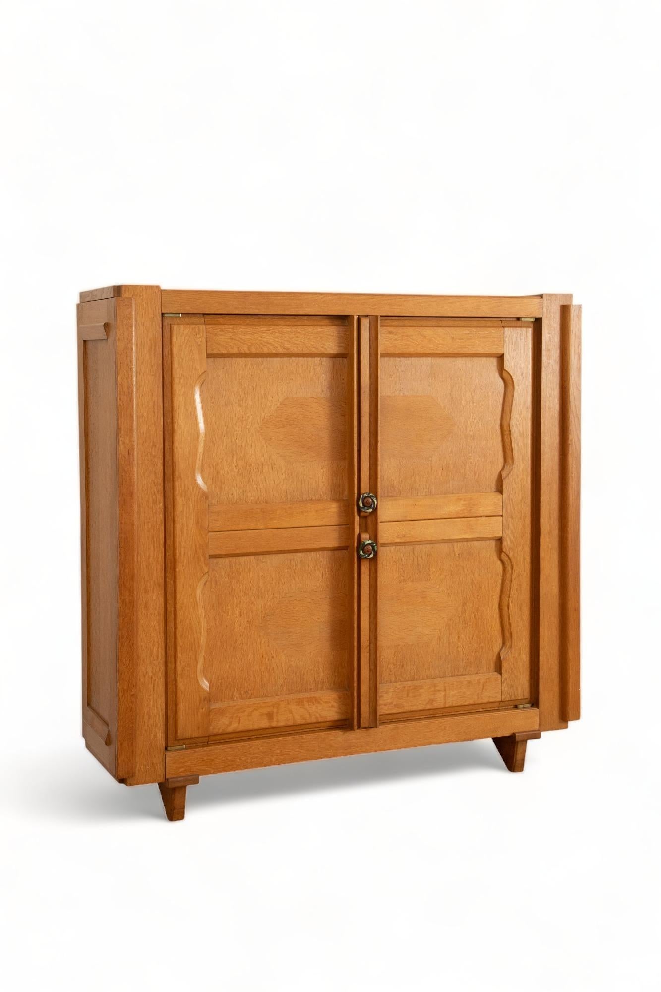 Two door oak cabinet cupboard by Guillerme et Chambron, France 1960
Front doors have decorative inlaid panels, with glazed ceramic handles by  artist Boleslaw Danikowski
Two front doors opening to four move-able shelves .
Two side doors with hidden