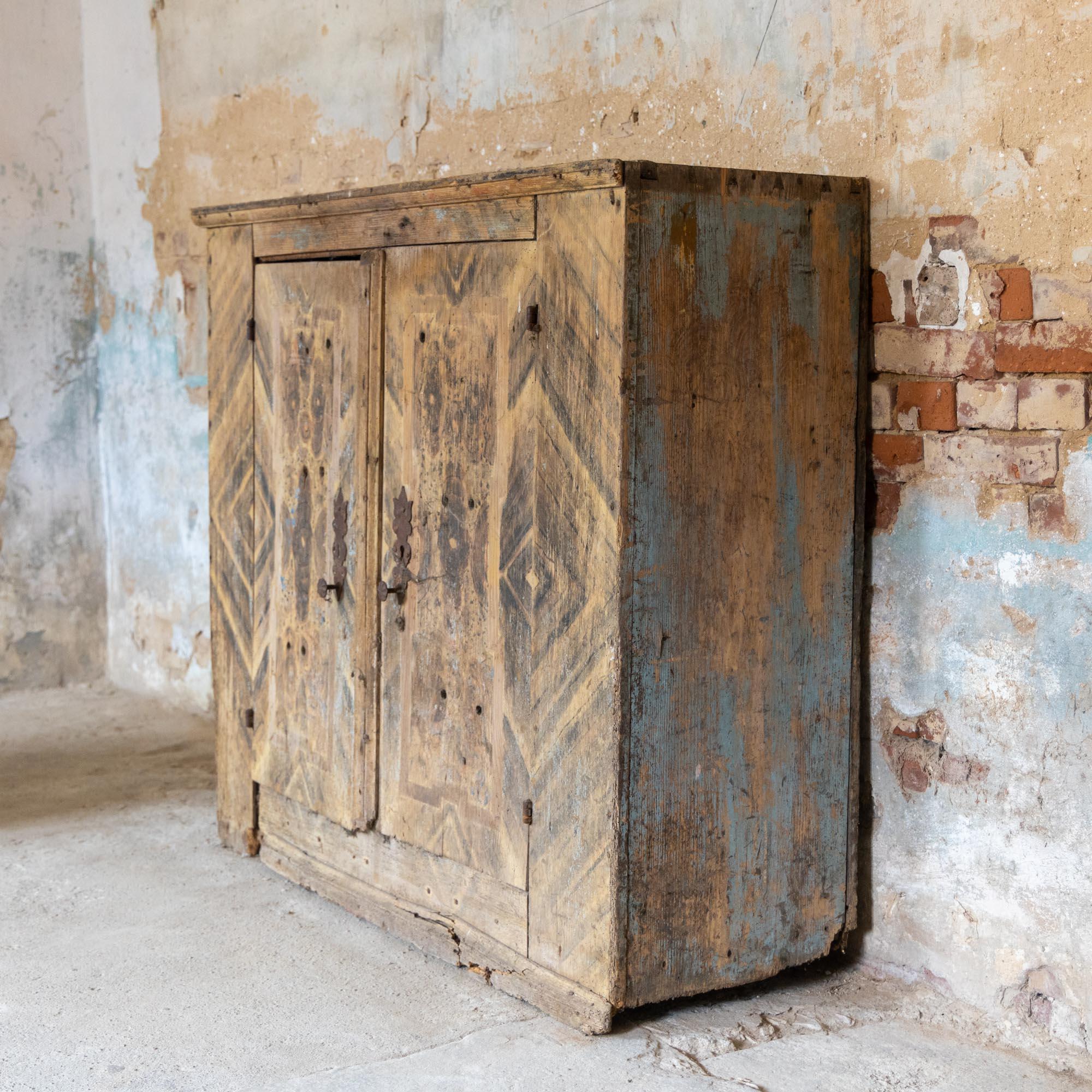 Two-door half cupboard of solid oak with wavy cut iron fittings and remnants of the old painting.