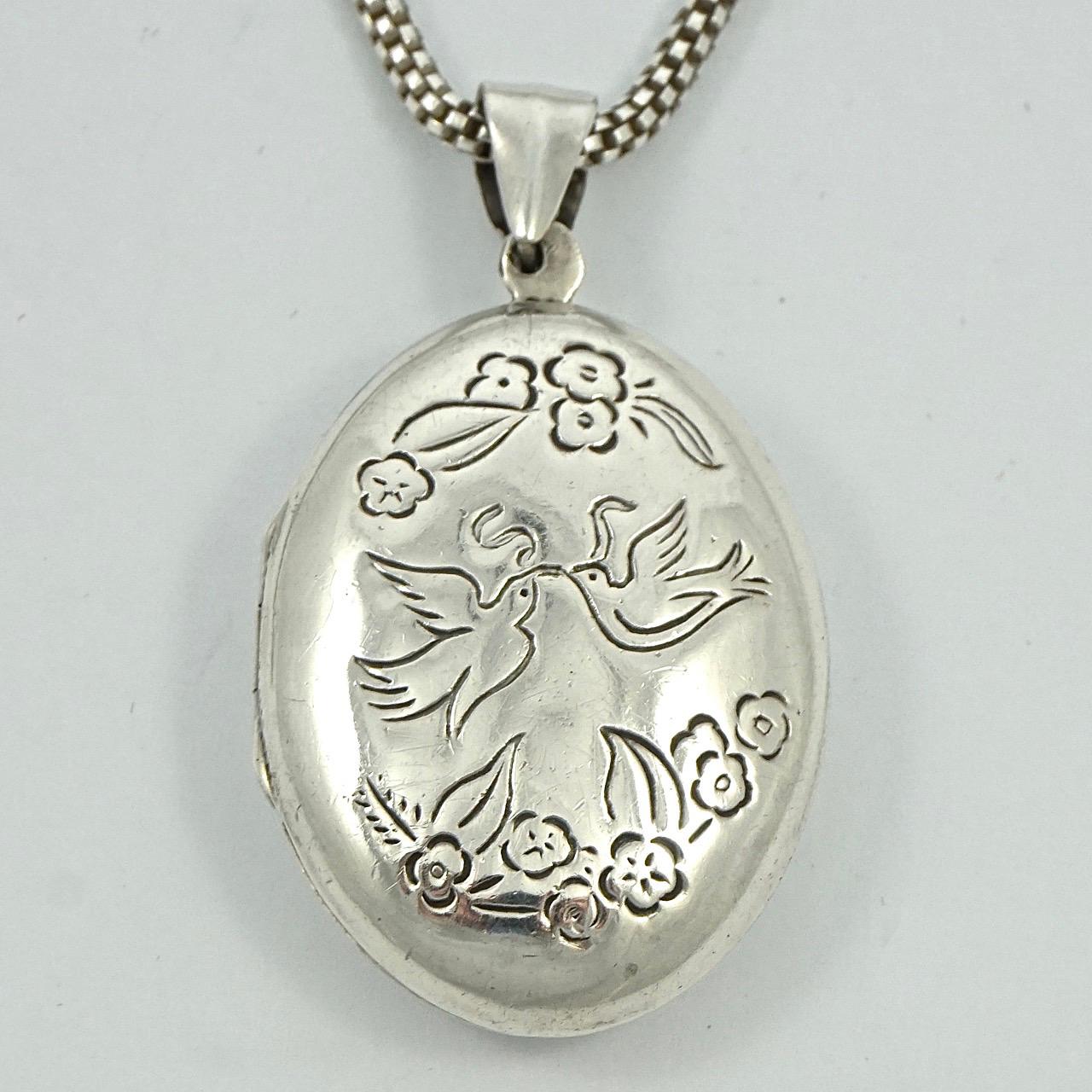 
Sterling silver large locket and mesh chain, featuring a beautiful doves and ribbon design with flower garlands to the front, and a verse to the back. The verse says 'How do I love thee ? Let me count the ways. I love thee to the depth and breadth