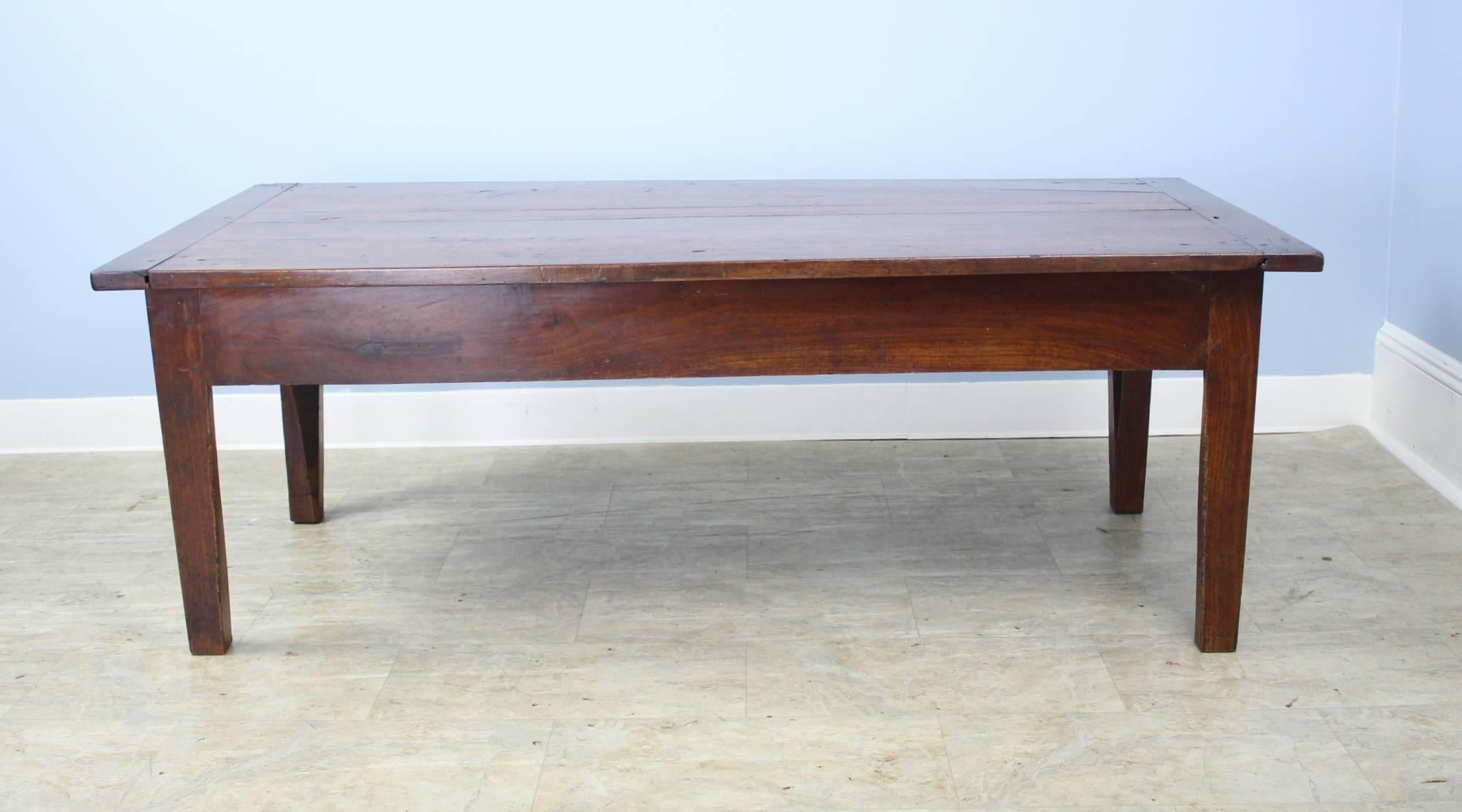 A chunky cherry coffee table with wonderful color and grain. The top has some interesting distress and classic breadboard ends. Solid legs, pegged at the apron, complete the look. Identical drawers at either end provide some storage.