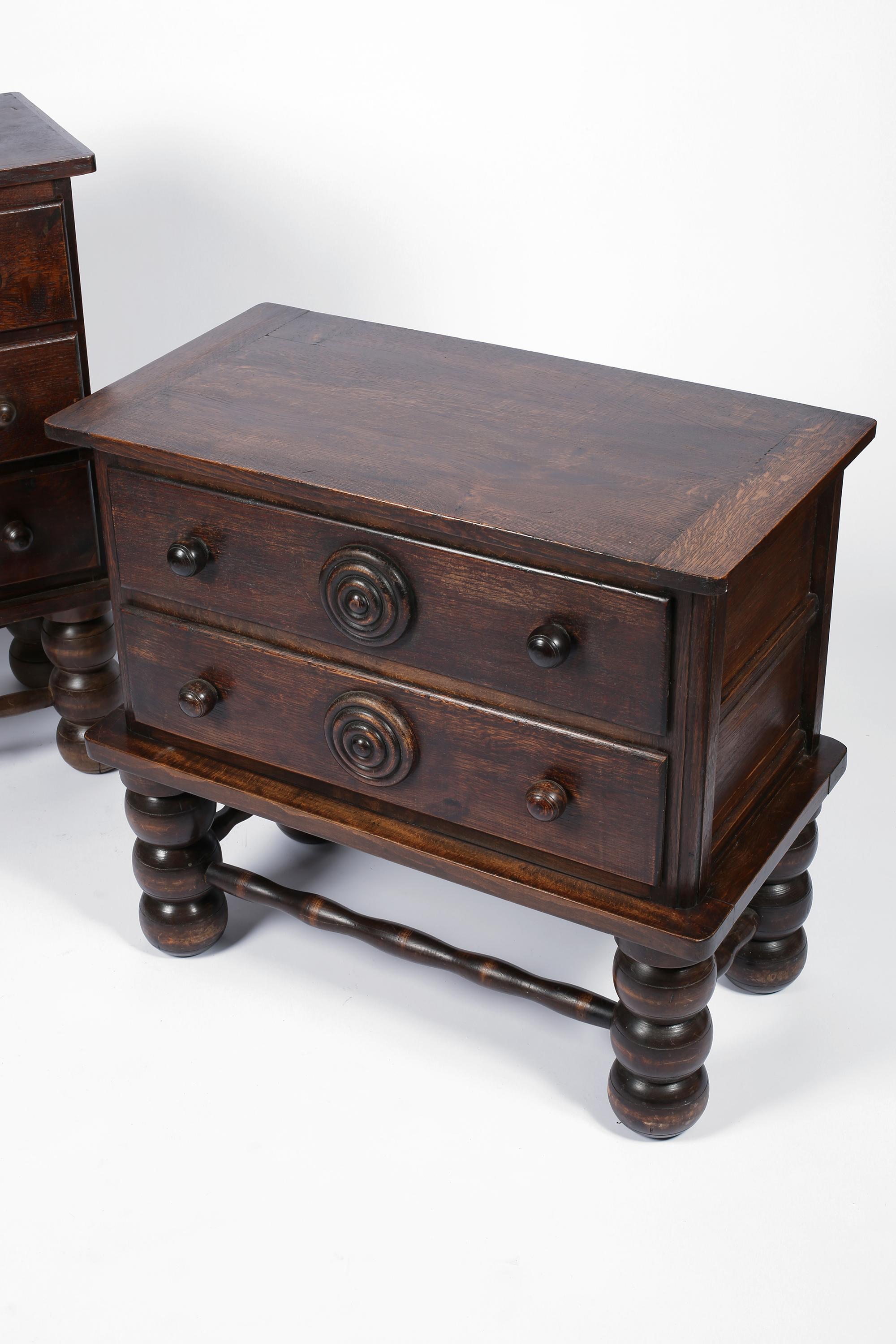 A two drawer chest of drawers by modernist designer Charles Dudouyt (1885-1946). Constructed from dark stained solid oak, featuring substantial bobbin turned legs and bulls eye detailing to the drawers. French, circa 1940.