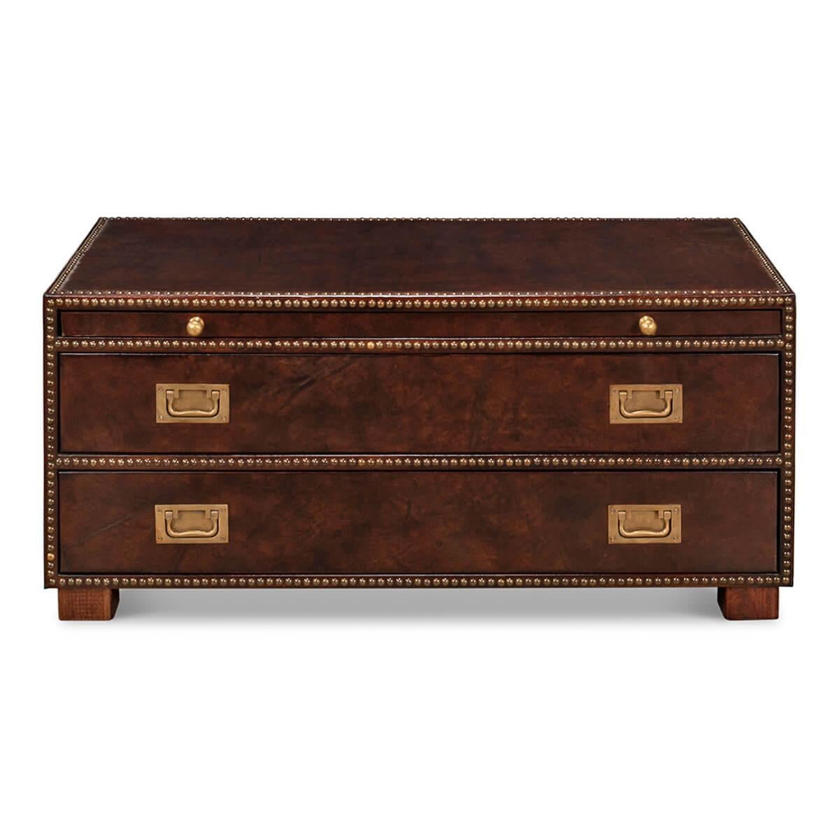 A two-drawer leather wrapped coffee table in the form of a low chest with brass nailhead trim. Covered in rich dark brown leather with brass accents, this chest has a luxurious look and feel. It has a practical design, including two drawers for