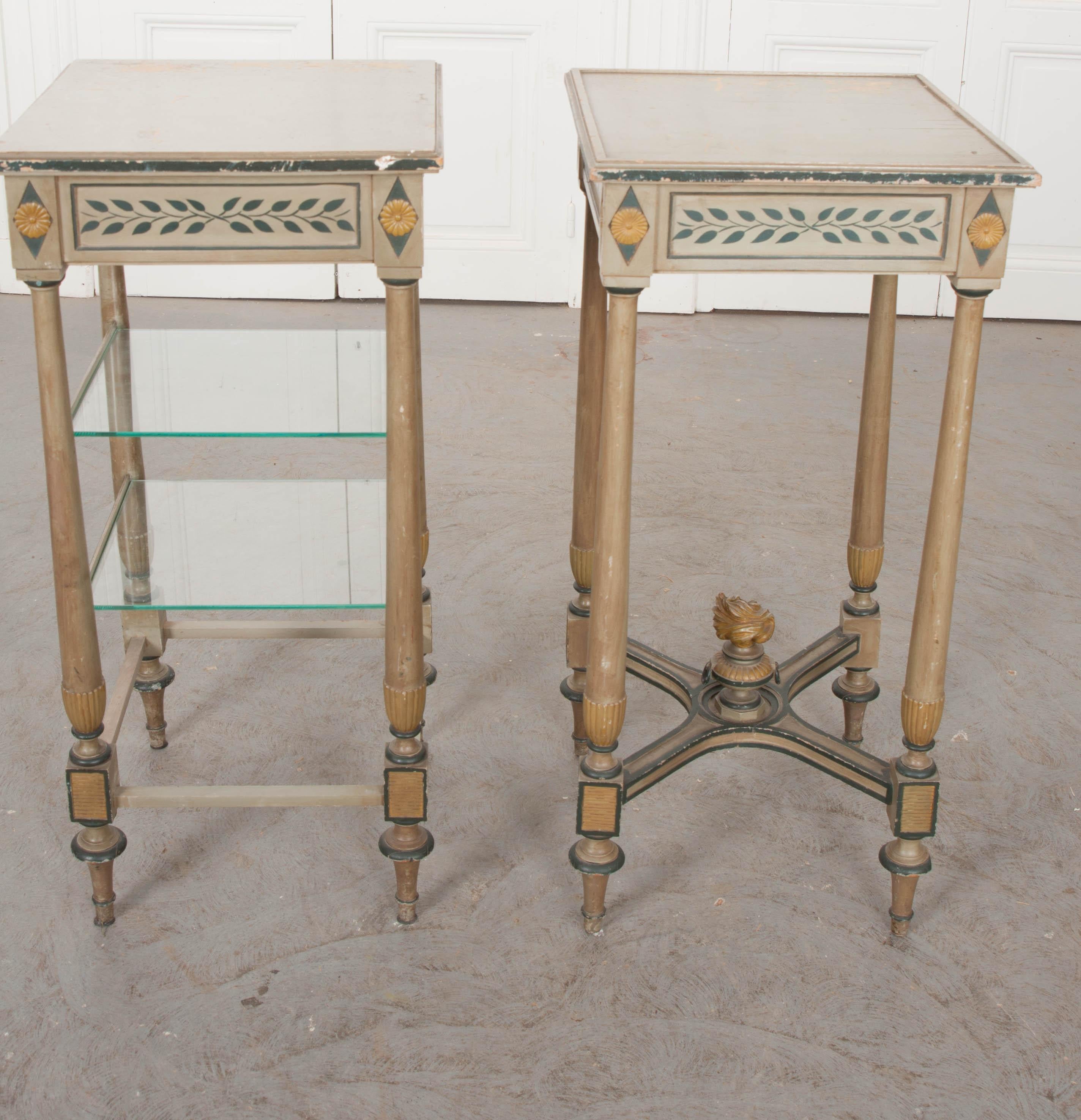These two delightful crème-painted Dutch side tables, circa 1910s, share the same leaf-and-rosette motifs and will pair well together. Each having a single drawer, however, one has been outfitted with a pair of glass shelves and the other has a