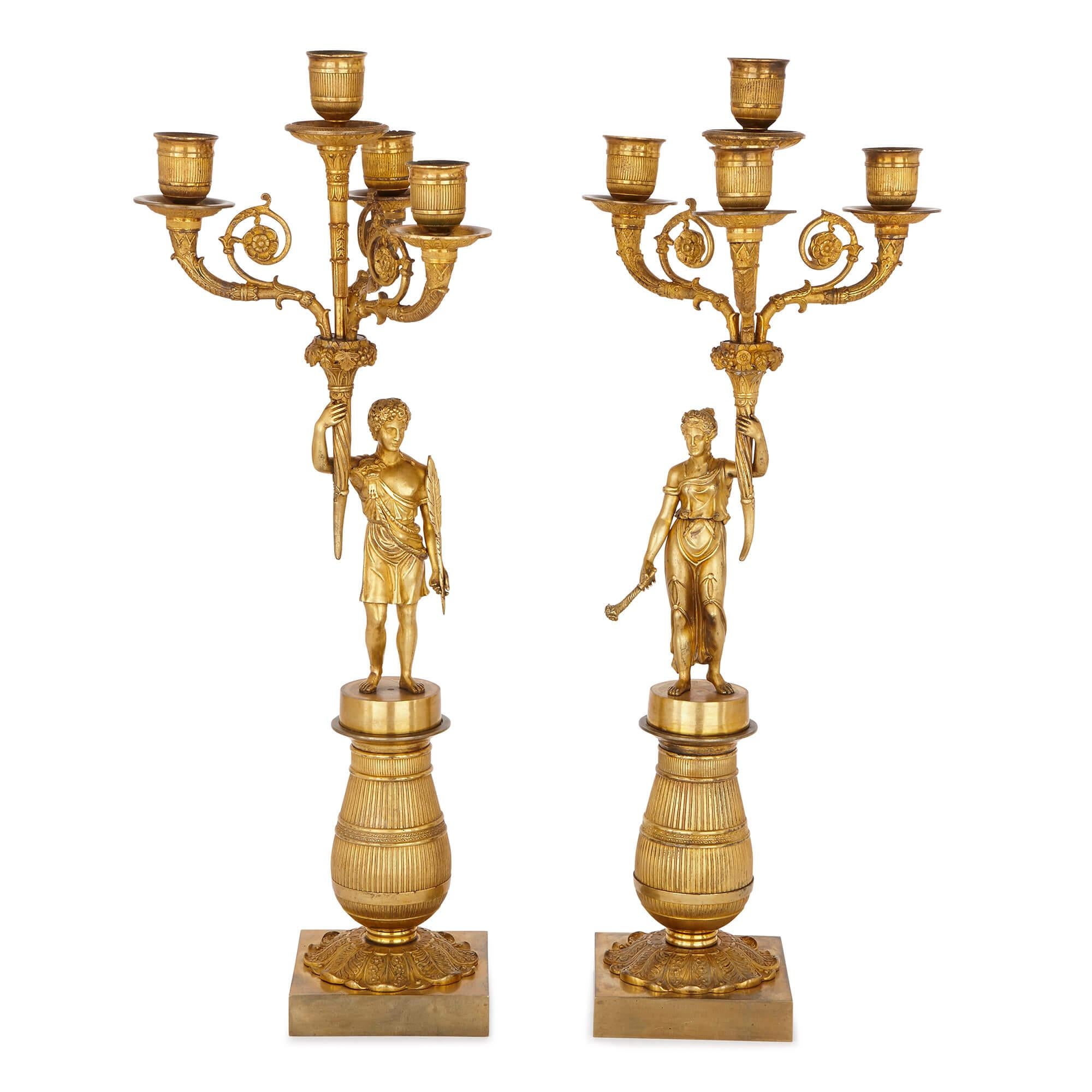 These magnificent candelabra were cast entirely of gilt bronze in the French Empire period of the early 19th century. Each candelabrum is formed as a cornucopia of scrolled branches holding four lights with drip pans, set on a single torch-form