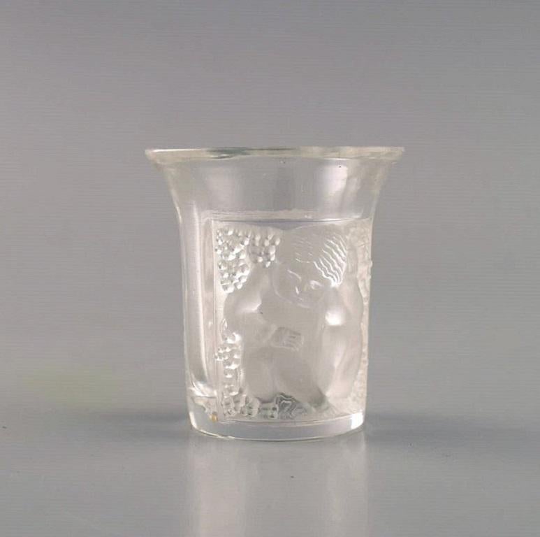 Two early René Lalique Enfants Art Deco shot glasses in mouth-blown crystal glass. 
1930s.
Measures: 4.7 x 4.2 cm.
Stamped: R. LALIQUE.
In good condition. Both glasses with a small chip.