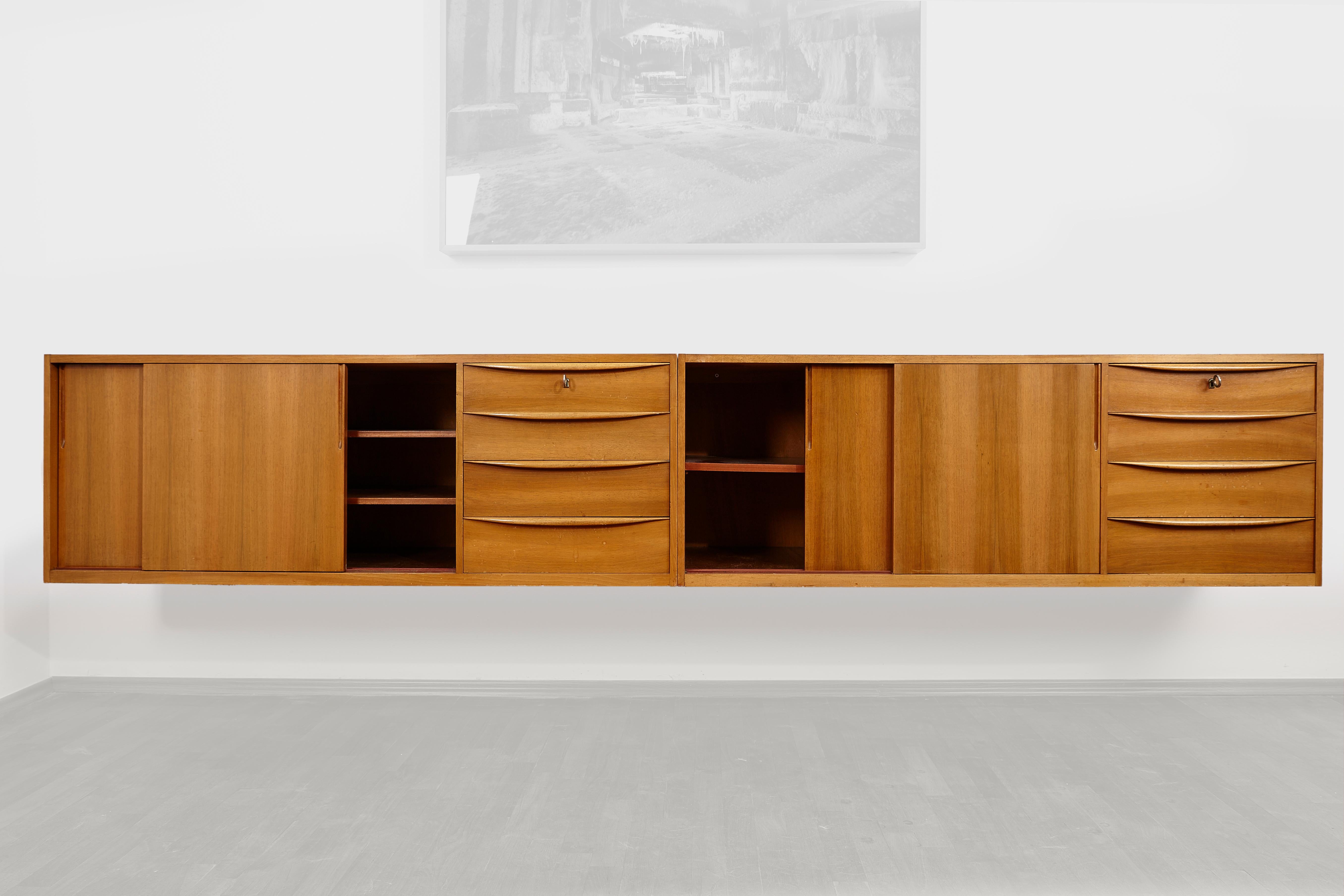 Two identical floating sideboards with sliding doors and unique elegant drawers in seldom walnut veneer. The sideboards are suspended and can complete each other or be separated.