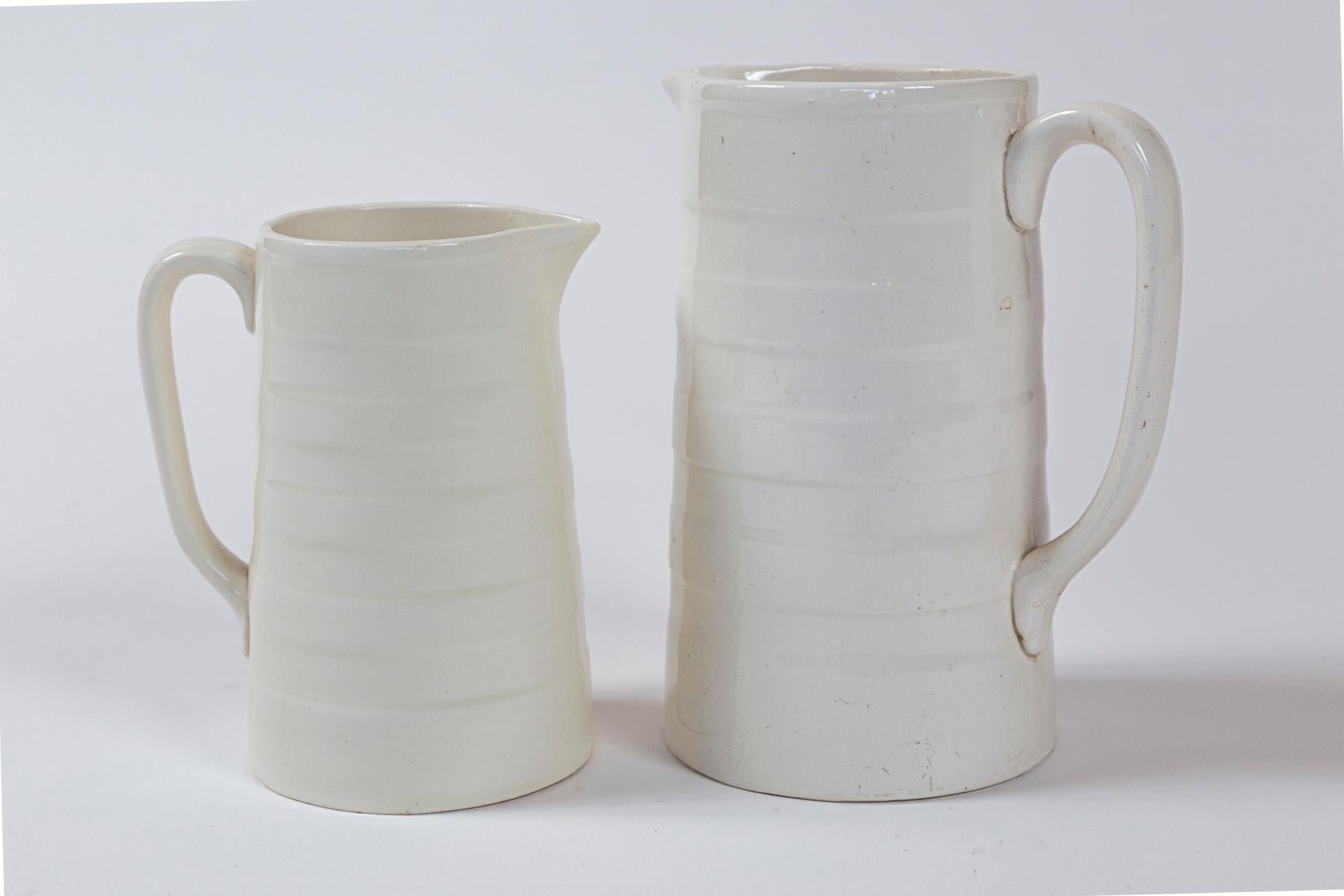 Two English Ironstone Dairy Pitchers, circa 1920s. Banded, white ironstone, straight sided pitchers.