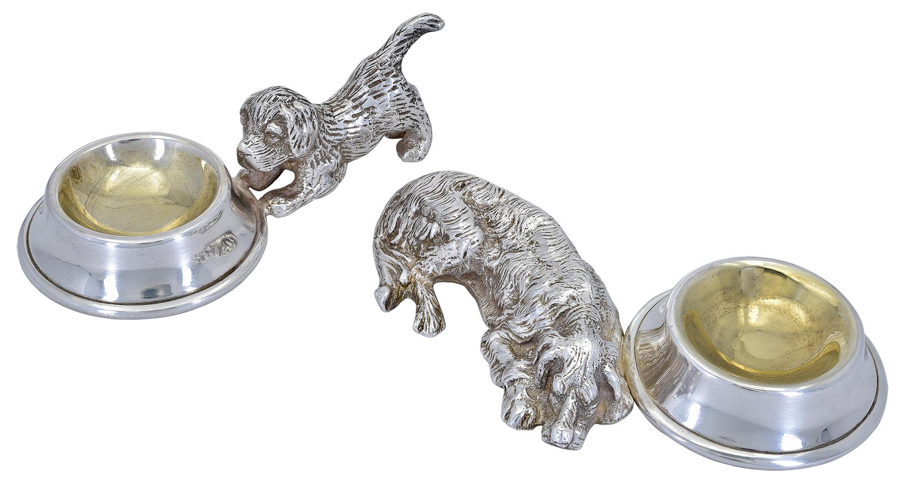 The best in show :  a pair of silver plate figural dogs with guilded bowls.  A large posed dog laying down next to a figural bowl with guilded interior, second dog is posed in a downward position next to a figural bowl with guilded interior.  