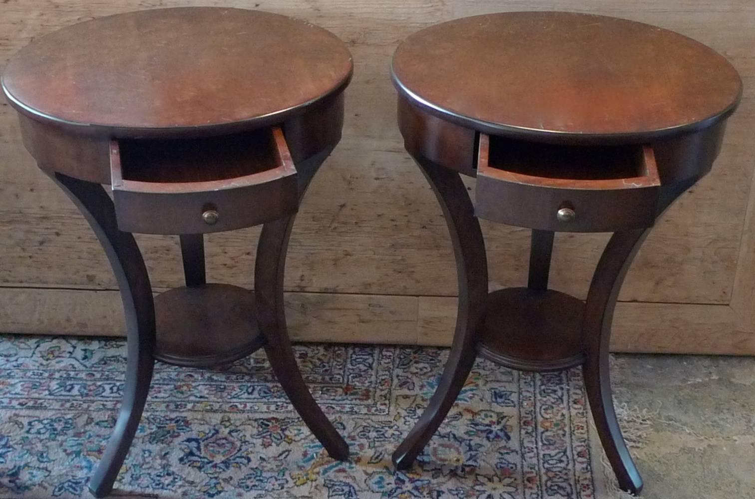 Two French 1970s walnut stained round side tables with one drawer and one shelf.