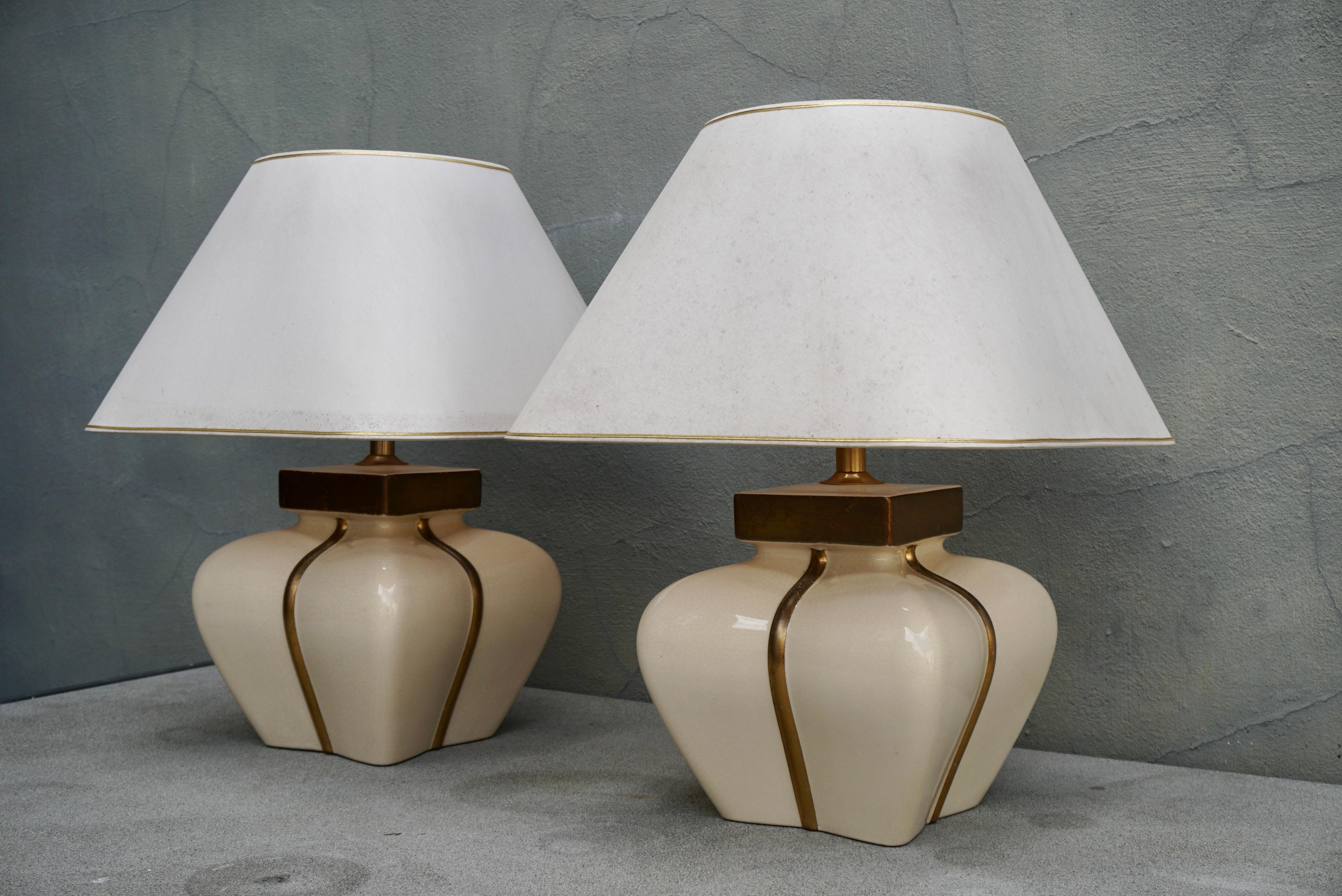 A pair tall high end French ceramic table lamps in cream and gold color.
Design: Maison Le Dauphin 
Style:Regency, Vintage, Mid Century 
Luxury lamps made of ceramic and gold gilded by Maison Le Dauphin Marked: Both lamps are marked on the back of