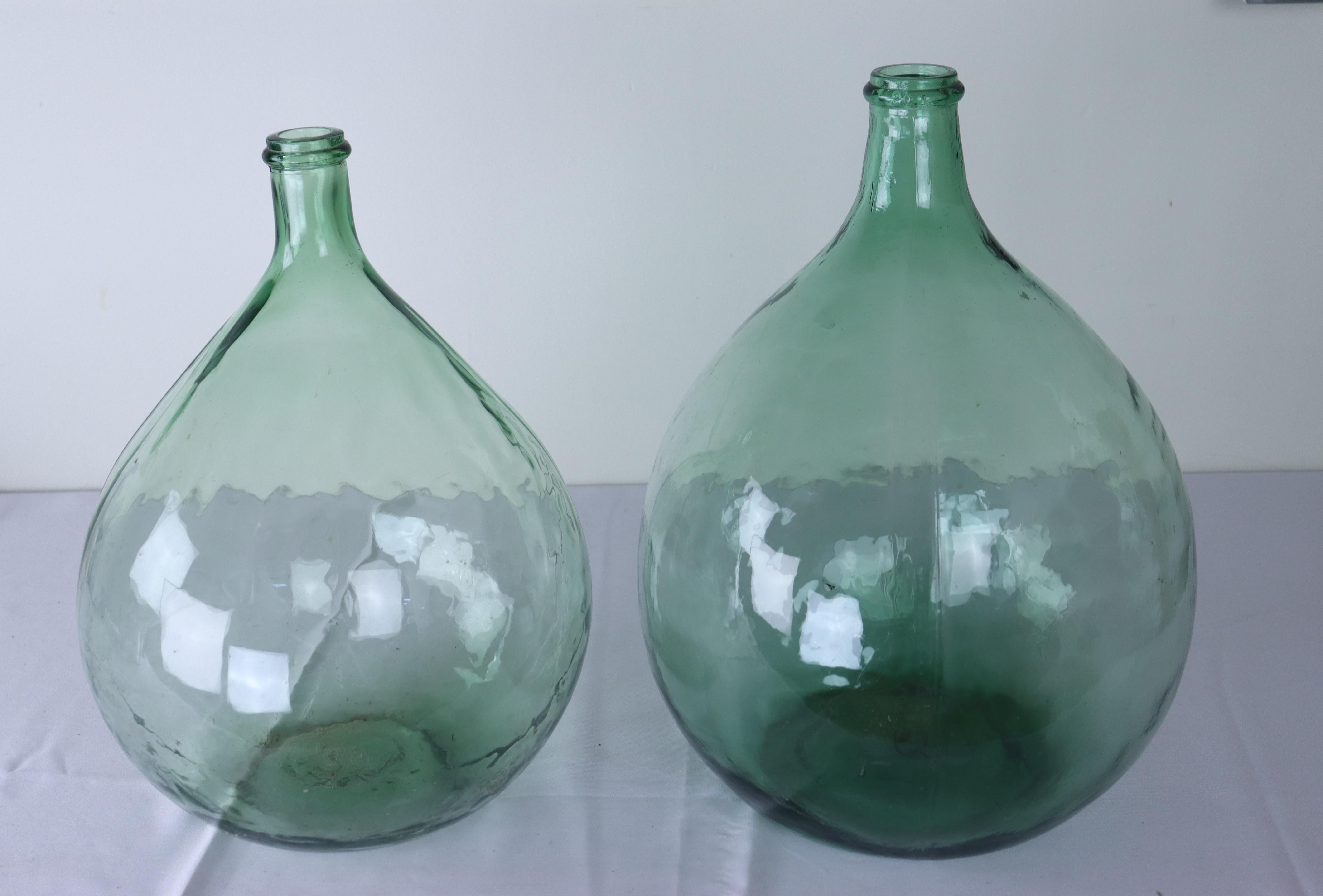 Two large French olive colored glass demijohn bottles.  We believe these to be modern reproductions of early 19th Century vessels. because of their intact bottle necks and the seam down the sides which might indicate machine made glass.  