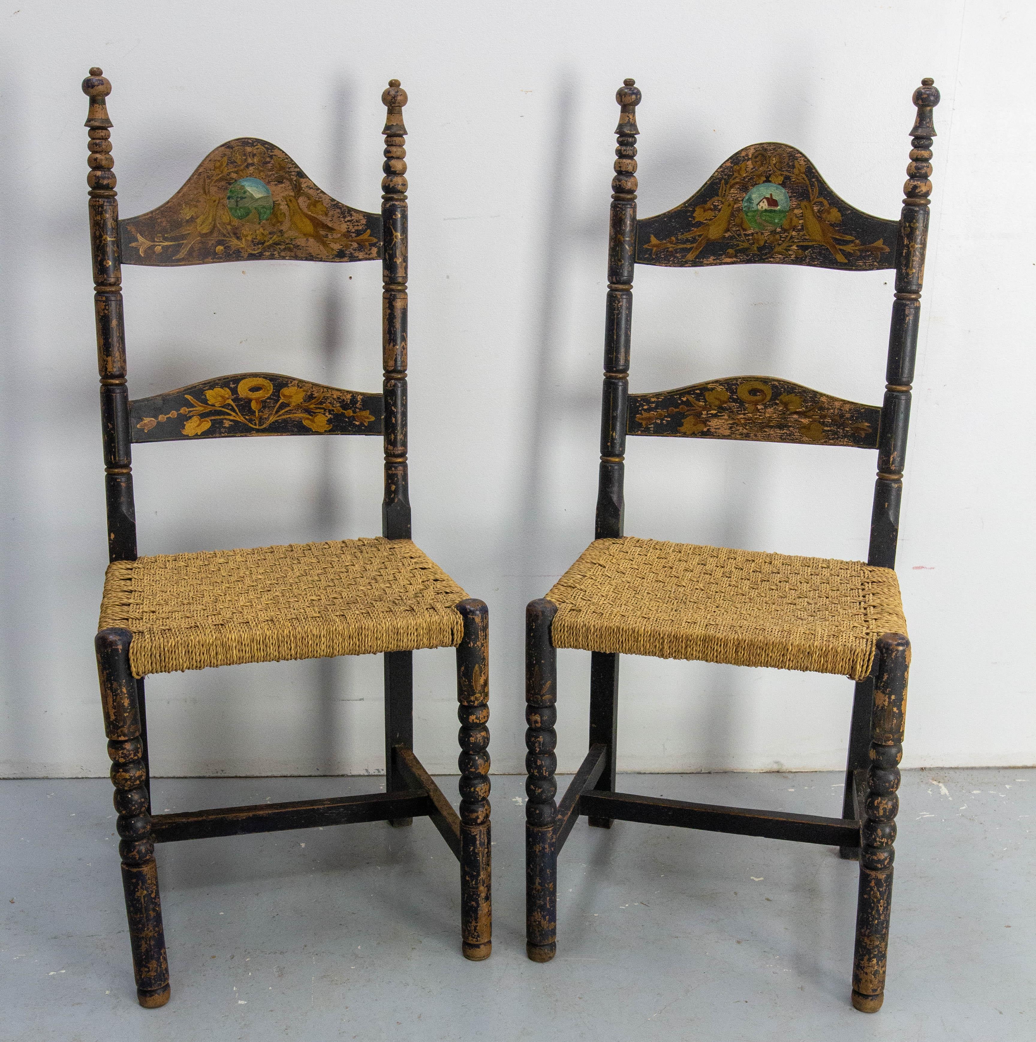 Paire de deux chaises latérales en hêtre de style provincial français, fabriquées au XIXe siècle.
Les sièges et les dossiers en jonc sont en bon état ancien.
Sur les dos, des oiseaux sont peints avec en médaillon un paysage et une maison.
Bon