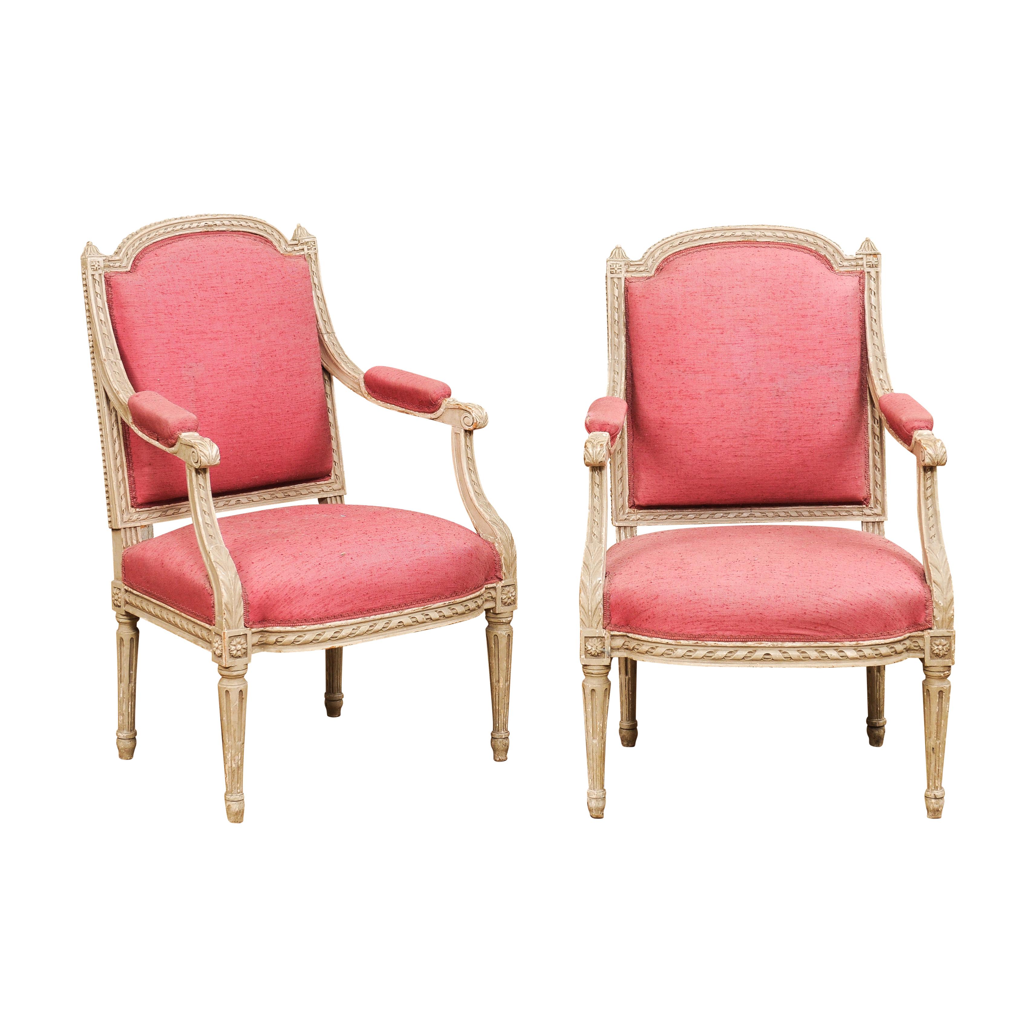 Two French Louis XVI style painted wood armchairs from the 19th century with carved décor including twisted rope motifs, acanthus leaves, rosettes and petite beads. Enhance your living space with the timeless elegance of these two French Louis XVI