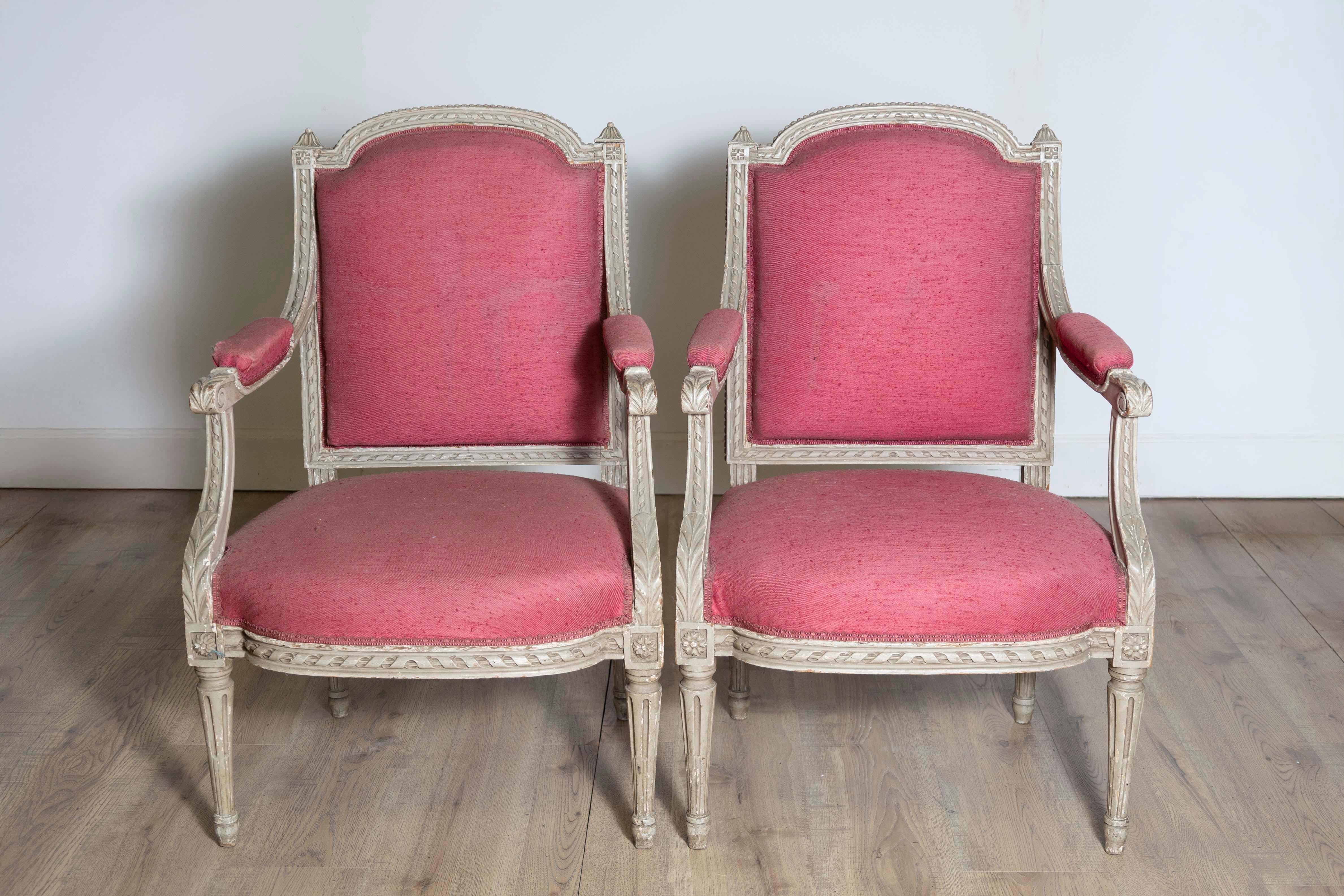 Two French Louis XVI style painted wood armchairs from the 19th century with carved décor including twisted rope motifs, acanthus leaves, rosettes and petite beads. Enhance your living space with the timeless elegance of these two French Louis XVI