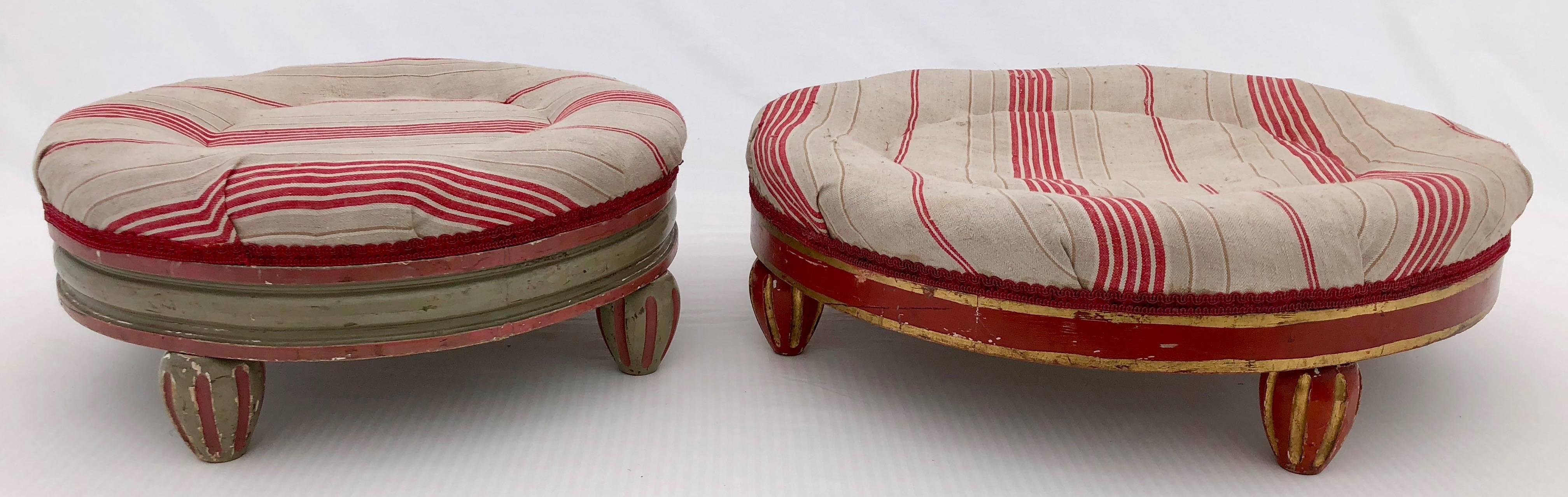 This is a set of two gorgeous French round footstools padded with hay and upholstered in an antique French red stripe linen. The larger footstool is hand-painted a lovely red with gold trim. The smaller footstool is hand-painted in a beautiful green