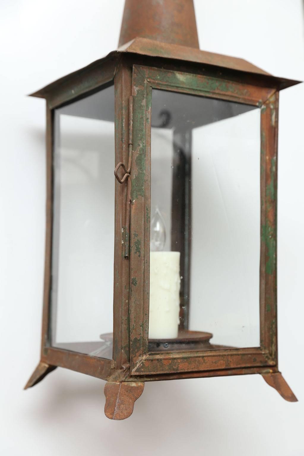 Two French tôle lanterns with remnants of original green paint and a rich patina. This pair of 19th century lanterns are each newly-wired for use within the USA and accommodates a single candelabra-size light. They include extra chain, canopies and
