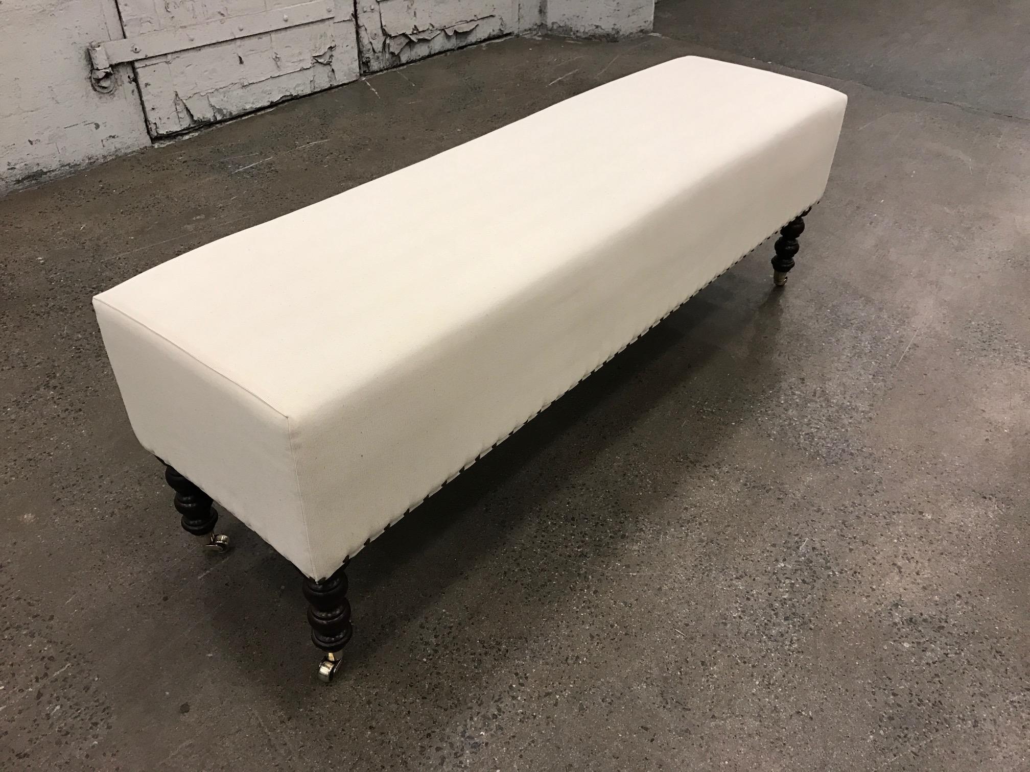 George Smith bench. The bench has solid walnut legs and brass casters.  One bench available.
  