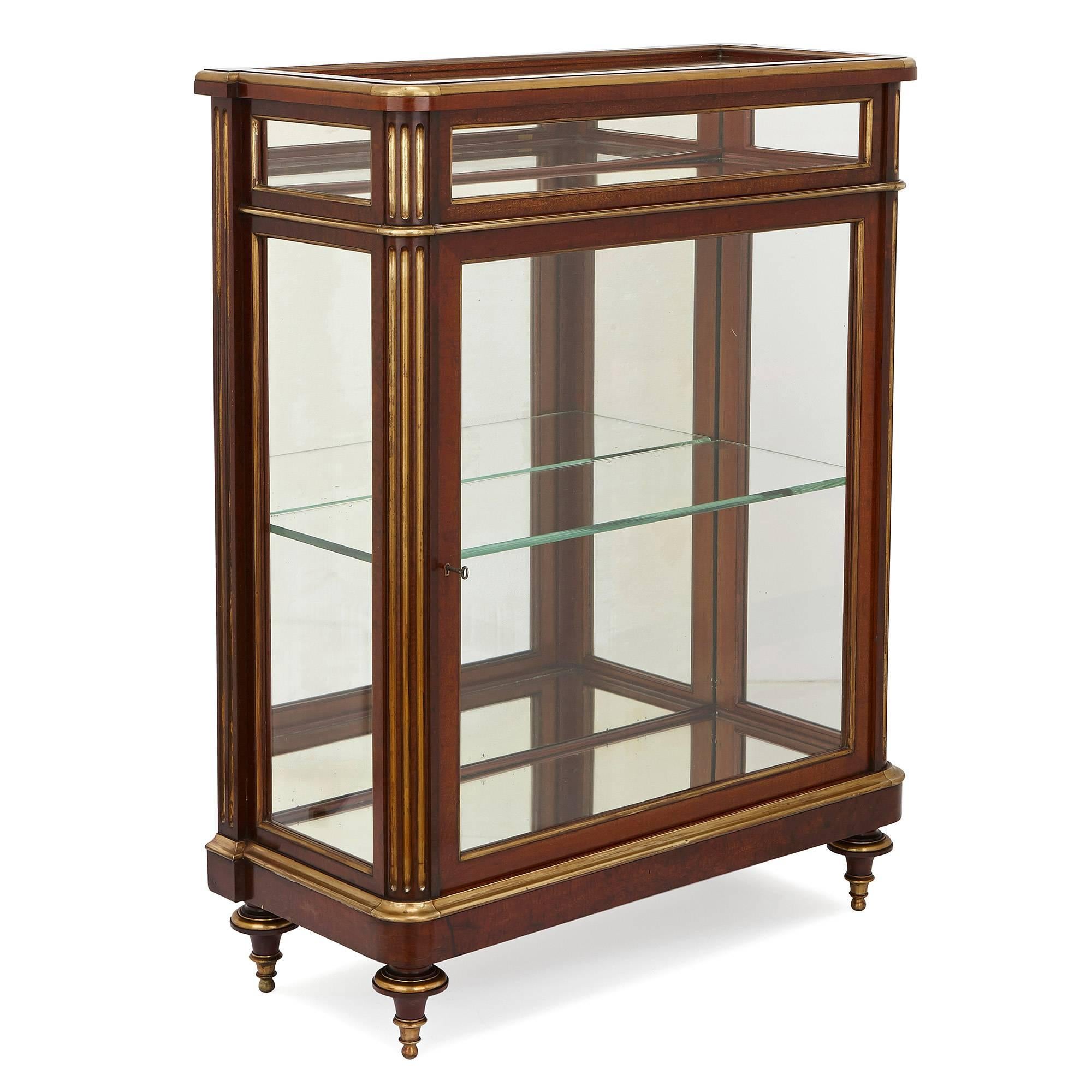 These refined display cabinets, or vitrines, are perfect for elegantly complimenting the display of trinkets without outshining them. The cabinets are crafted in rectangular form from mahogany and highlighted with gleaming brass. Set on four toupie